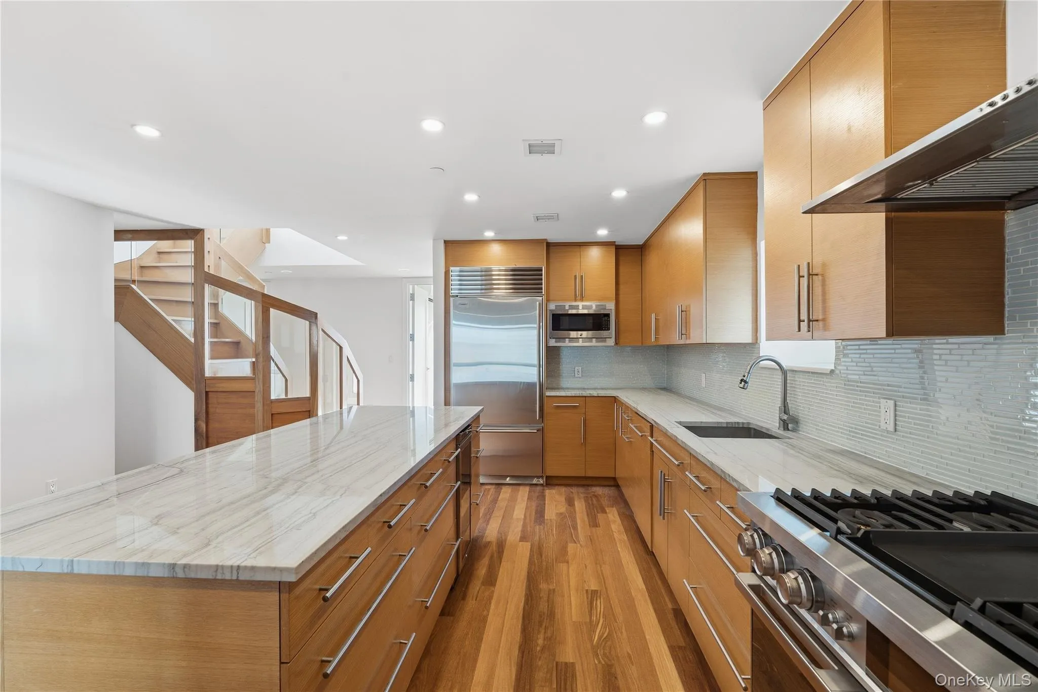 Kitchen with light stone counters, built in appliances, tasteful backsplash, ventilation hood, and recessed lighting Kitchen with light stone counters, built in appliances, tasteful backsplash, ventilation hood, and recessed lighting