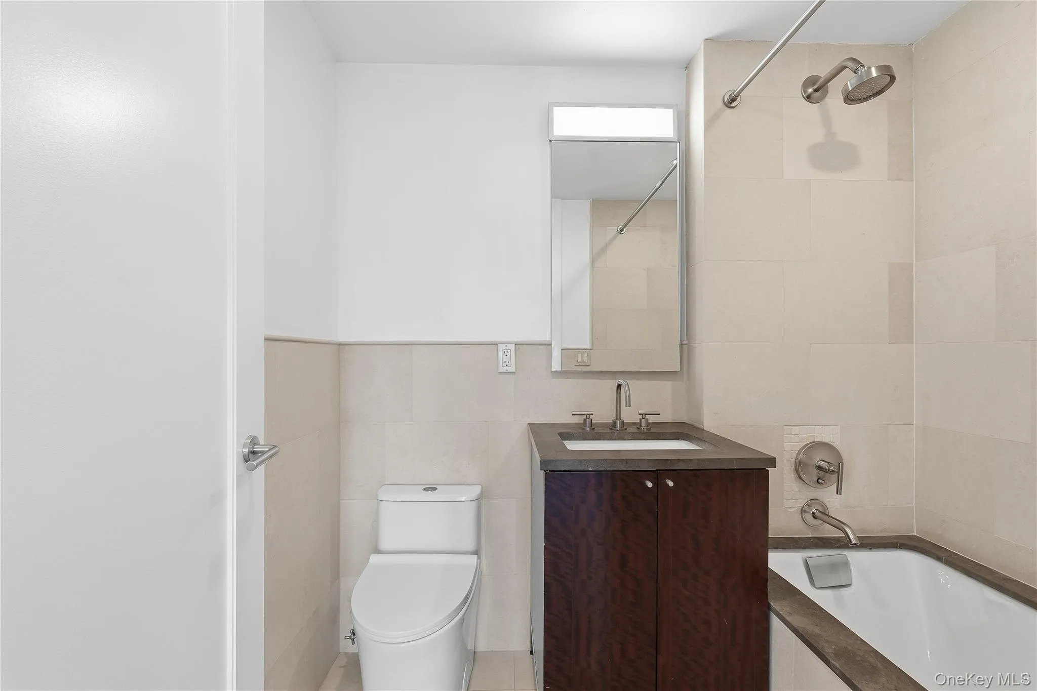 Bathroom with vanity, tile walls, and shower / washtub combination Bathroom with vanity, tile walls, and shower / washtub combination