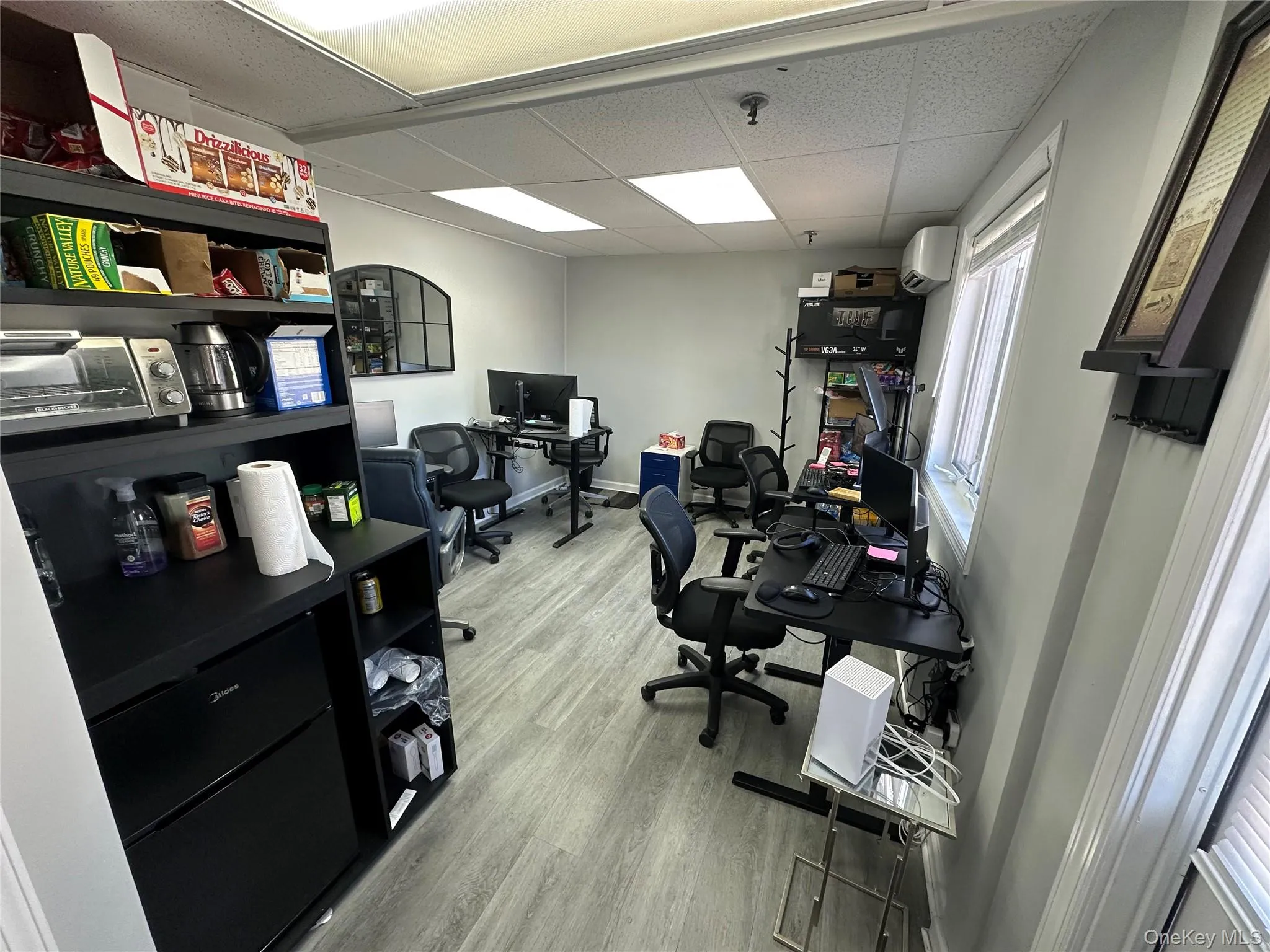 Office area featuring a drop ceiling, light wood-type flooring, and a wall mounted AC Office area featuring a drop ceiling, light wood-type flooring, and a wall mounted AC