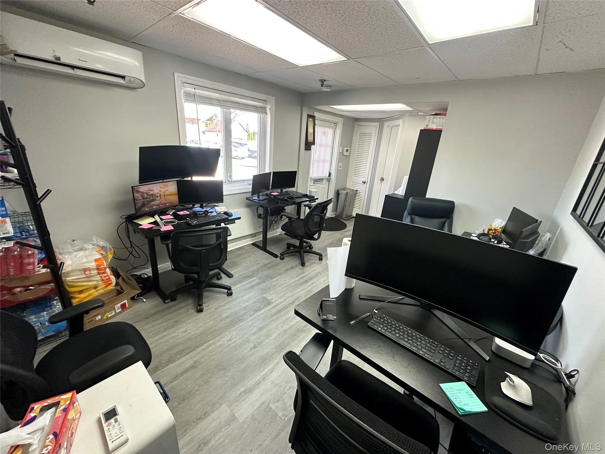 Home office featuring a paneled ceiling, a wall mounted air conditioner, and light wood-style flooring Home office featuring a paneled ceiling, a wall mounted air conditioner, and light wood-style flooring