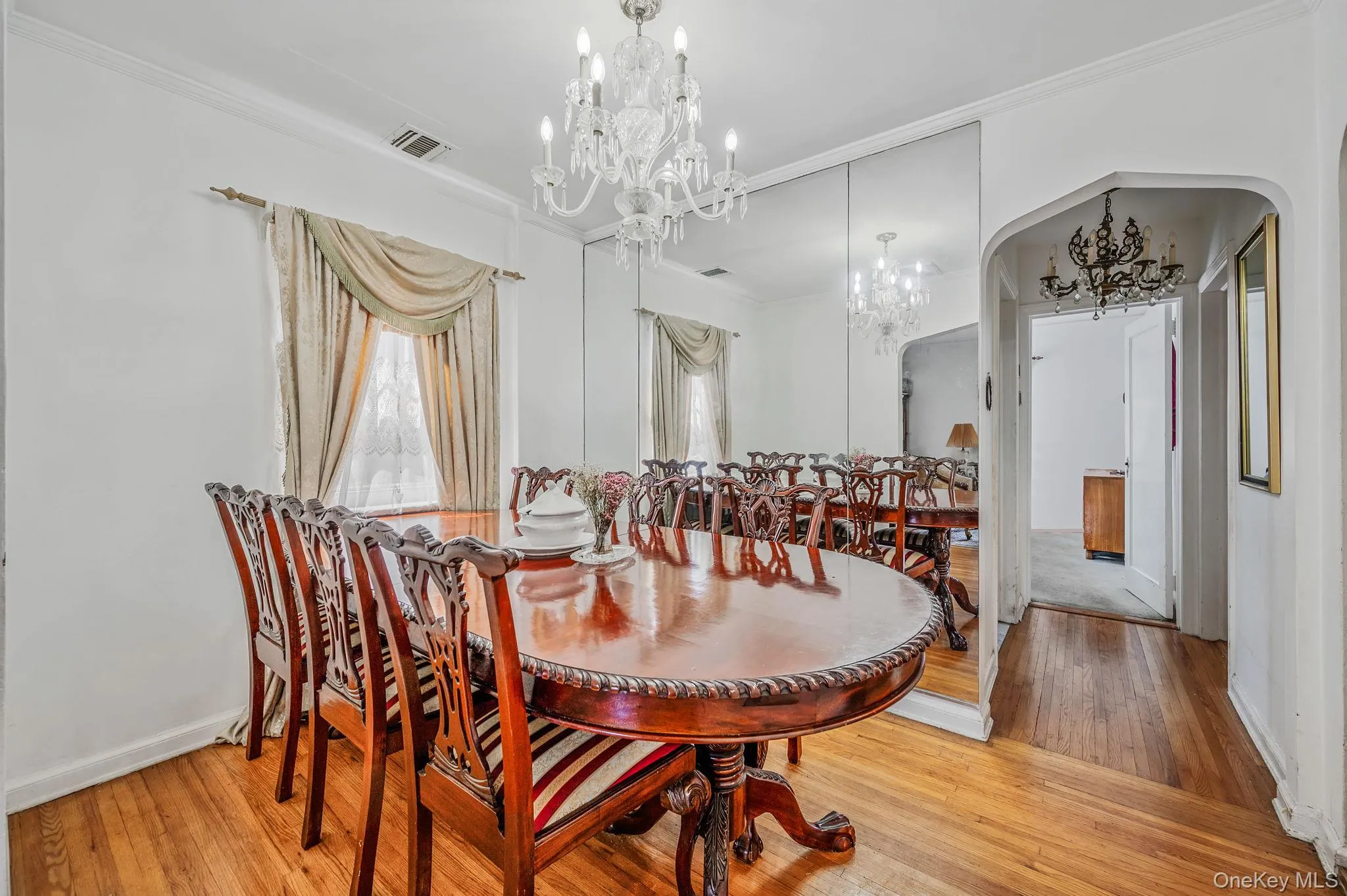 Dining room featuring light wood-style flooring, crown molding, arched walkways, and a chandelier Dining room featuring light wood-style flooring, crown molding, arched walkways, and a chandelier