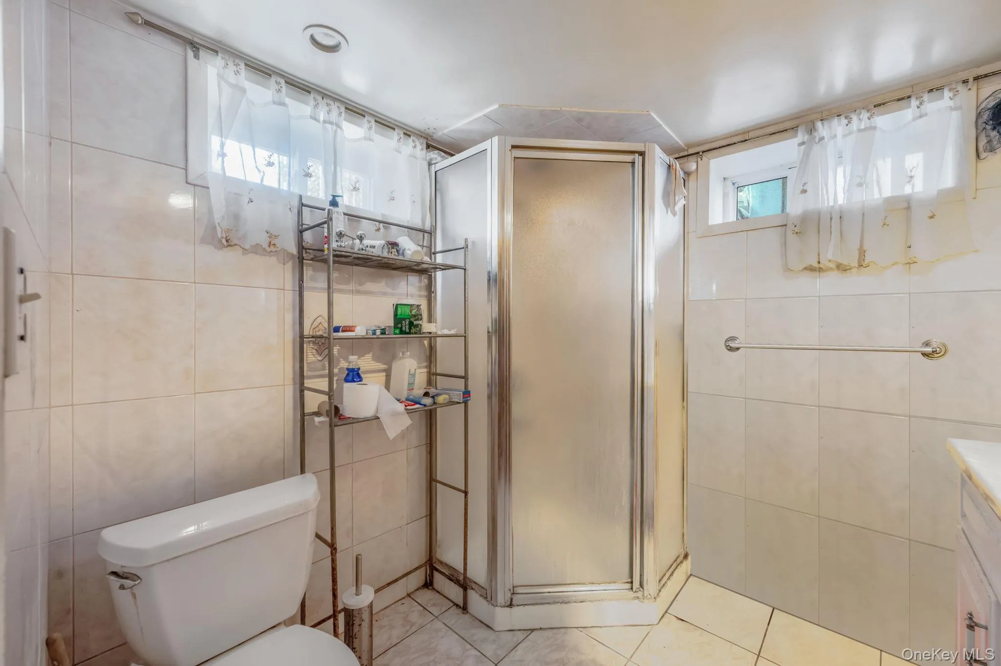 Full bath with tile walls, a stall shower, light tile patterned floors, and vanity Full bath with tile walls, a stall shower, light tile patterned floors, and vanity