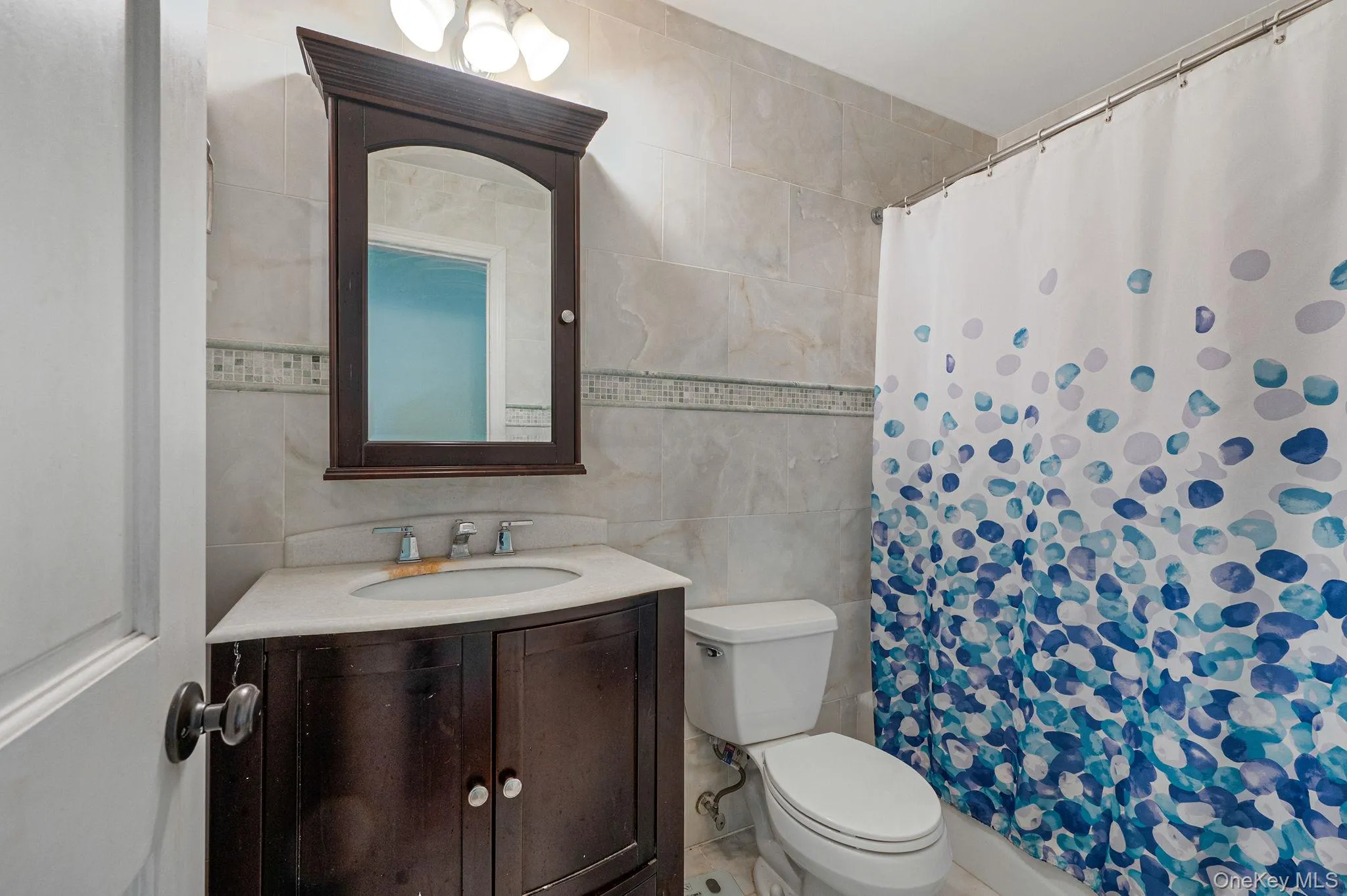 Bathroom with tile walls, vanity, and a shower with curtain Bathroom with tile walls, vanity, and a shower with curtain