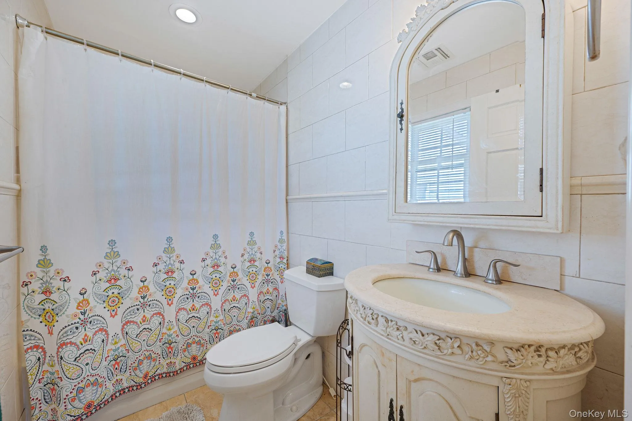 Full bath with tile walls, vanity, light tile patterned floors, and shower / bath combo with shower curtain Full bath with tile walls, vanity, light tile patterned floors, and shower / bath combo with shower curtain