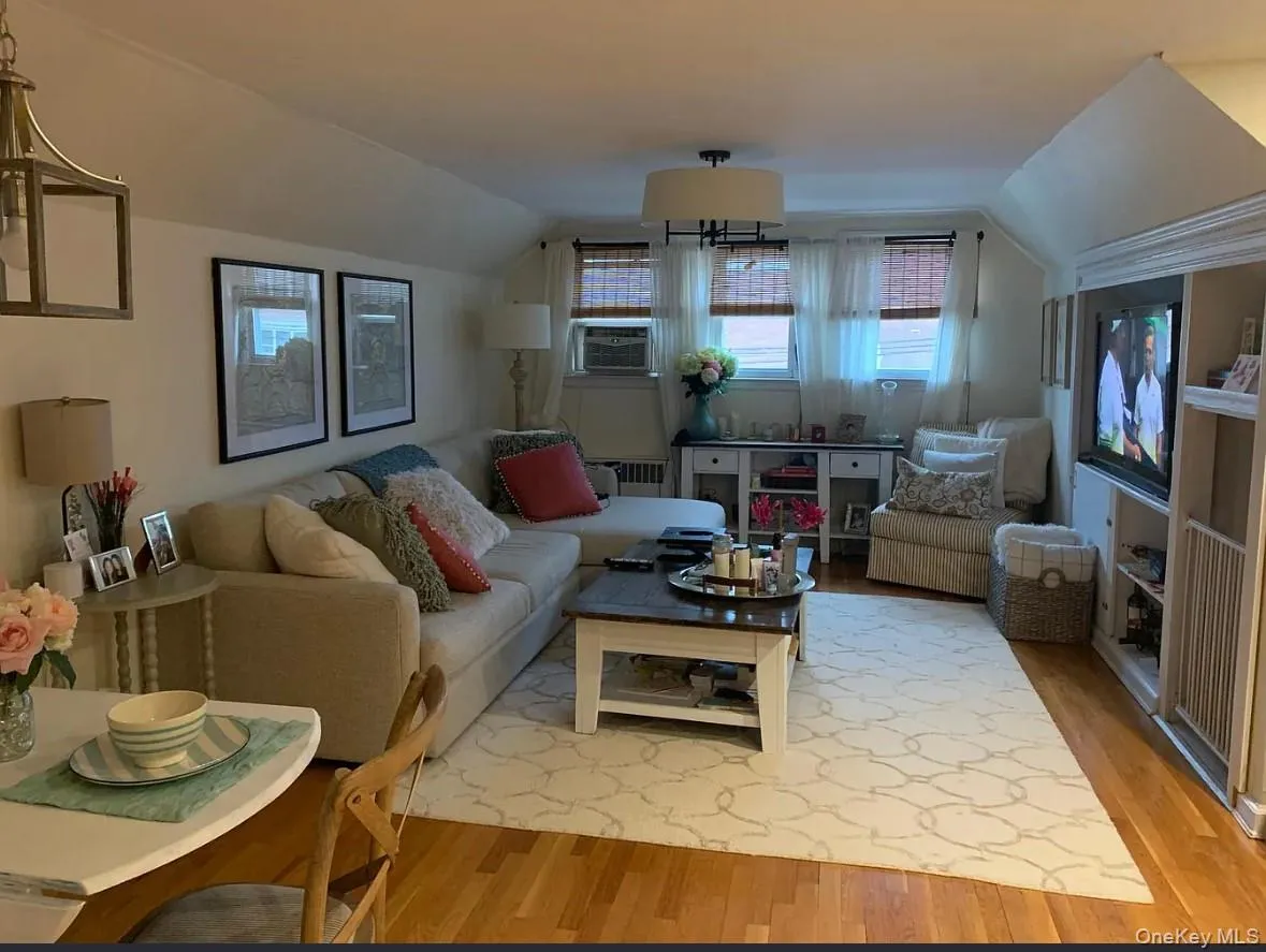 Living area with vaulted ceiling, wood finished floors, and radiator Living area with vaulted ceiling, wood finished floors, and radiator