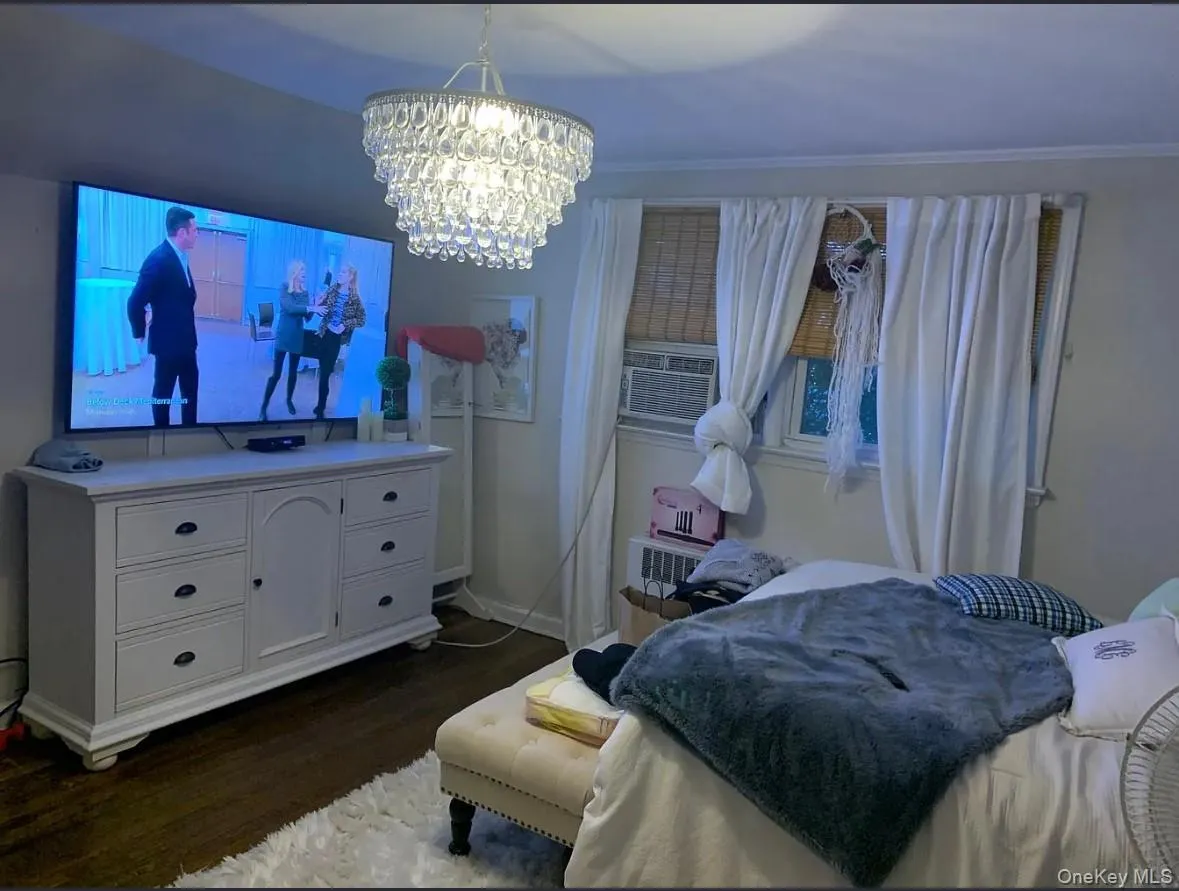 Bedroom with dark wood-style flooring, cooling unit, and a chandelier Bedroom with dark wood-style flooring, cooling unit, and a chandelier