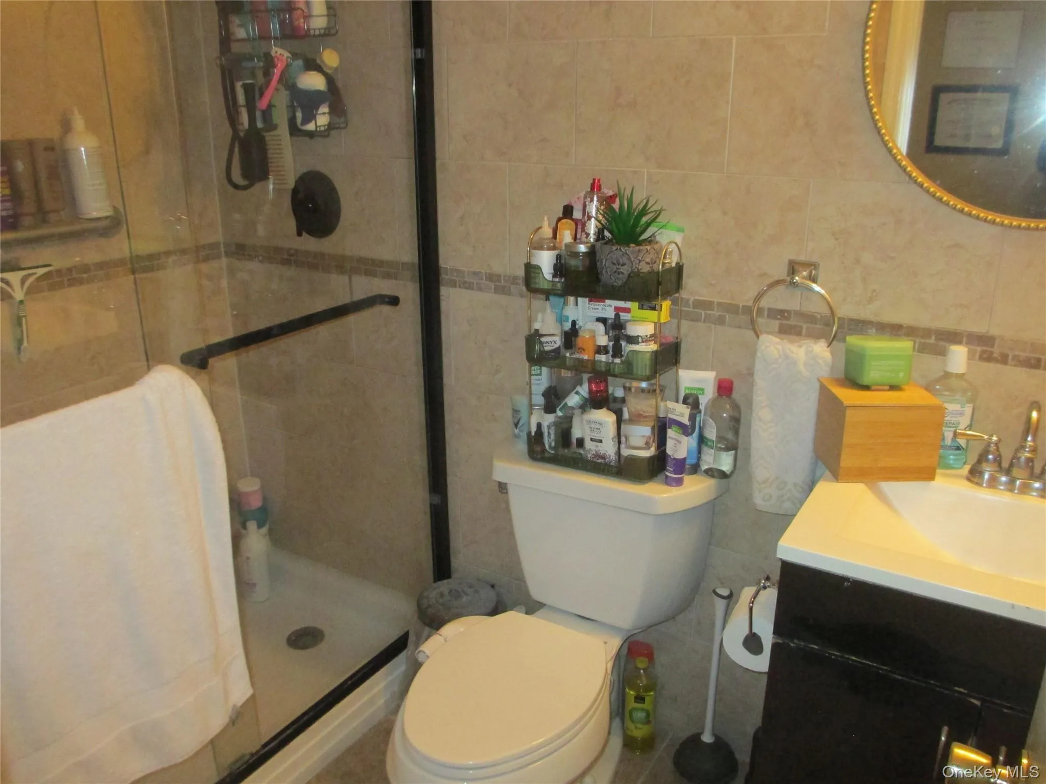 Bathroom featuring tile walls, vanity, a shower stall, and backsplash Bathroom featuring tile walls, vanity, a shower stall, and backsplash