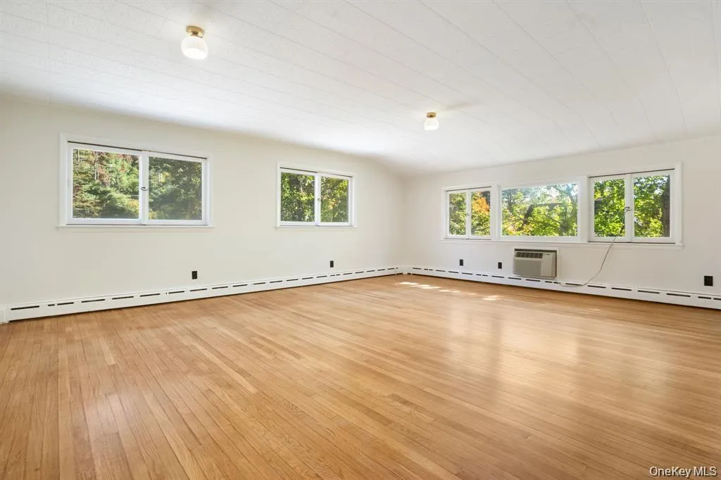Unfurnished room with plenty of natural light, light wood finished floors, and baseboard heating Unfurnished room with plenty of natural light, light wood finished floors, and baseboard heating