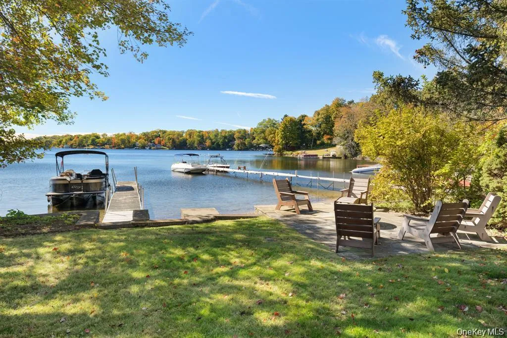 Dock area featuring a water view, a yard, a forest view, and a patio area Dock area featuring a water view, a yard, a forest view, and a patio area