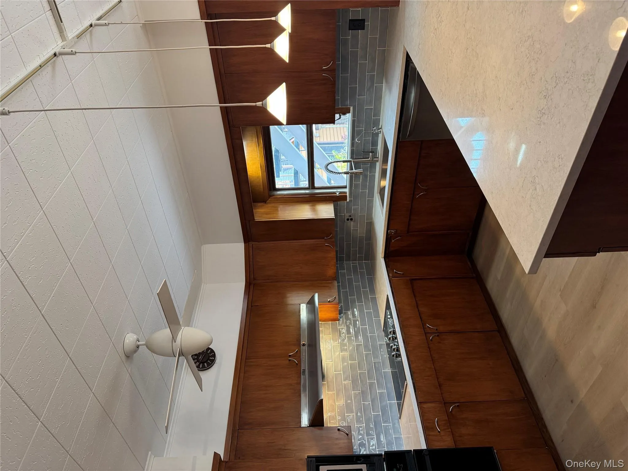 Kitchen featuring tasteful backsplash, decorative light fixtures, light wood-style floors, and light stone countertops Kitchen featuring tasteful backsplash, decorative light fixtures, light wood-style floors, and light stone countertops