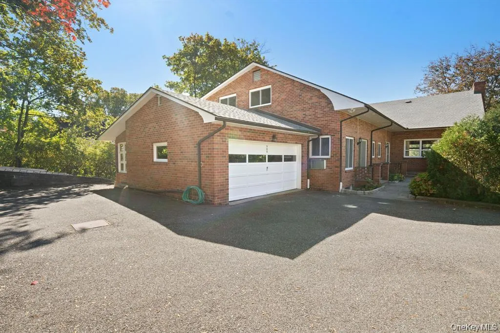 View of side of property featuring brick siding, asphalt driveway, a garage, and a chimney View of side of property featuring brick siding, asphalt driveway, a garage, and a chimney