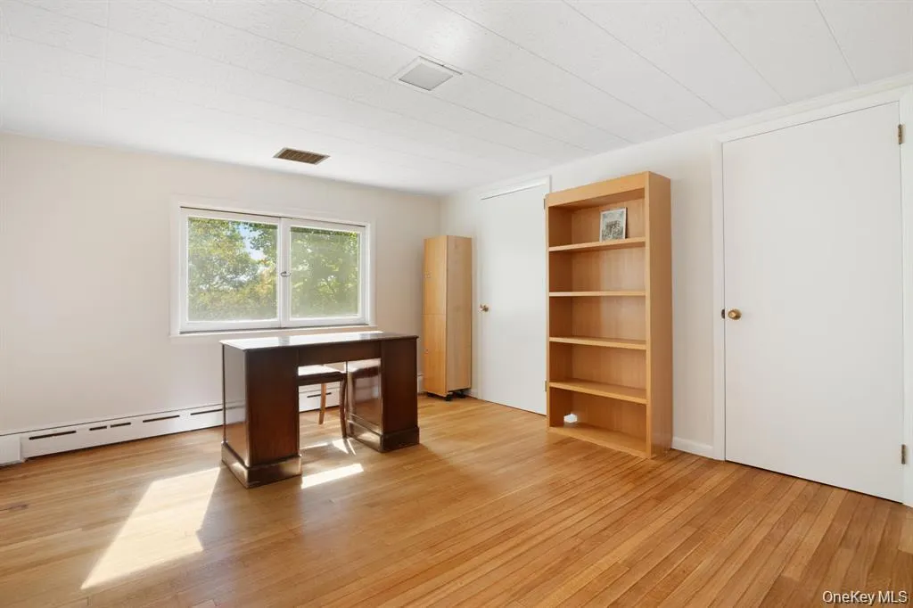 Unfurnished office featuring light wood-style floors and baseboard heating Unfurnished office featuring light wood-style floors and baseboard heating