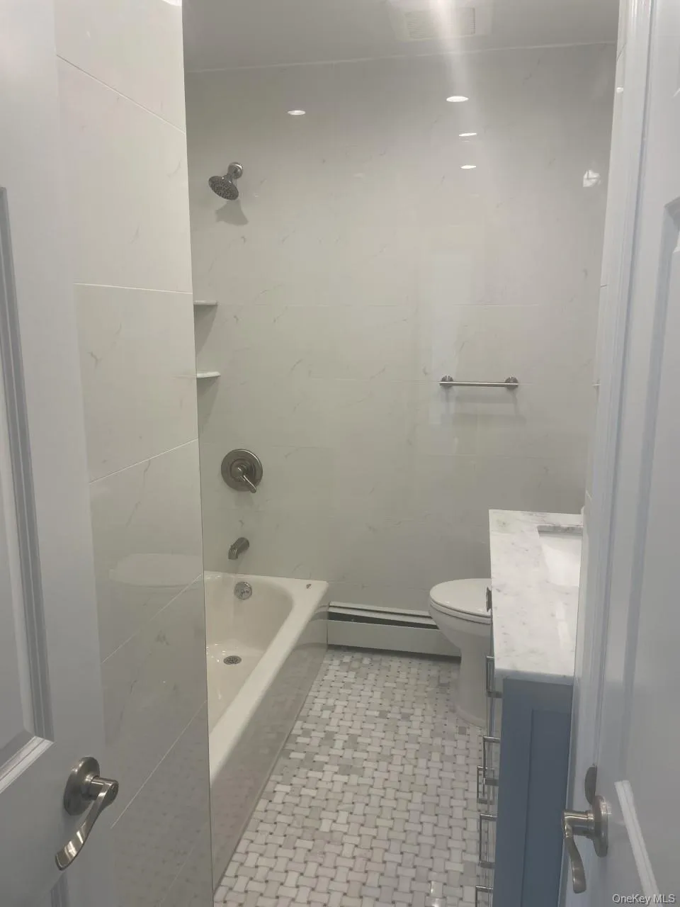 Full bathroom with vanity, shower / bathtub combination, a baseboard radiator, and light tile patterned floors Full bathroom with vanity, shower / bathtub combination, a baseboard radiator, and light tile patterned floors