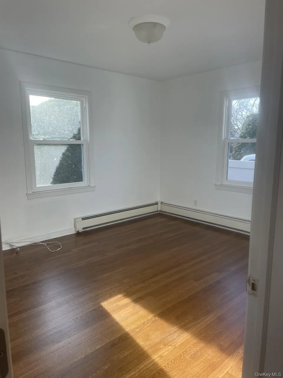 Spare room with dark wood-style floors and baseboard heating Spare room with dark wood-style floors and baseboard heating