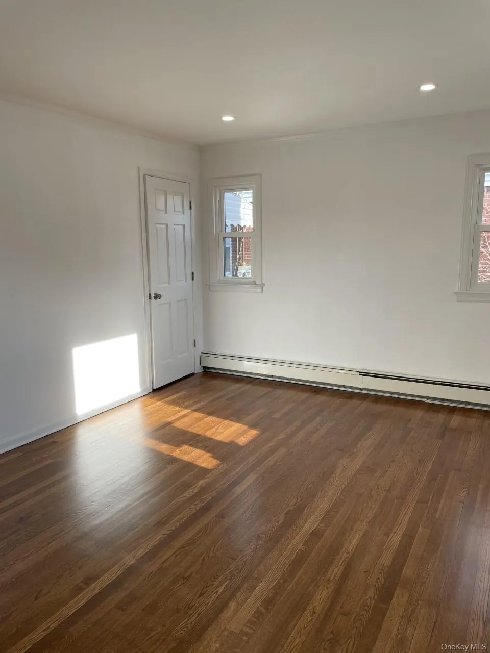 Unfurnished room with baseboard heating, ornamental molding, dark wood-style floors, and recessed lighting Unfurnished room with baseboard heating, ornamental molding, dark wood-style floors, and recessed lighting