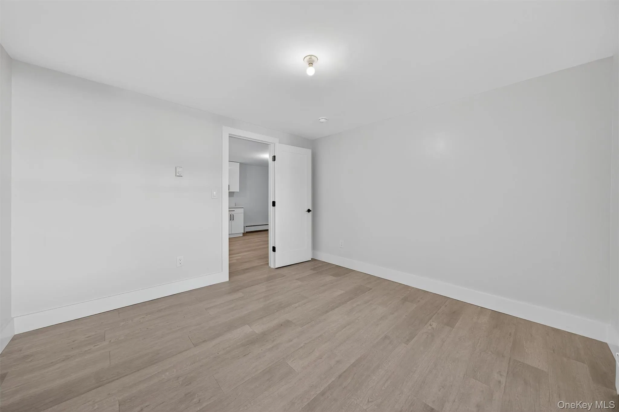 Empty room featuring light wood-style flooring and a baseboard heating unit Empty room featuring light wood-style flooring and a baseboard heating unit