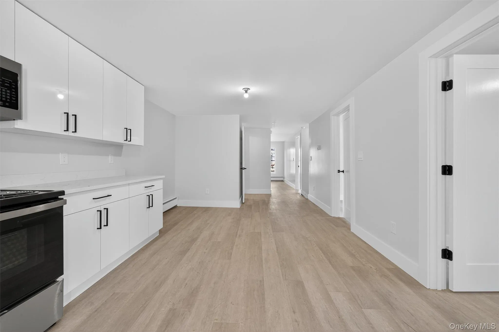 Kitchen featuring stainless steel appliances, white cabinetry, light wood-type flooring, and modern cabinets Kitchen featuring stainless steel appliances, white cabinetry, light wood-type flooring, and modern cabinets