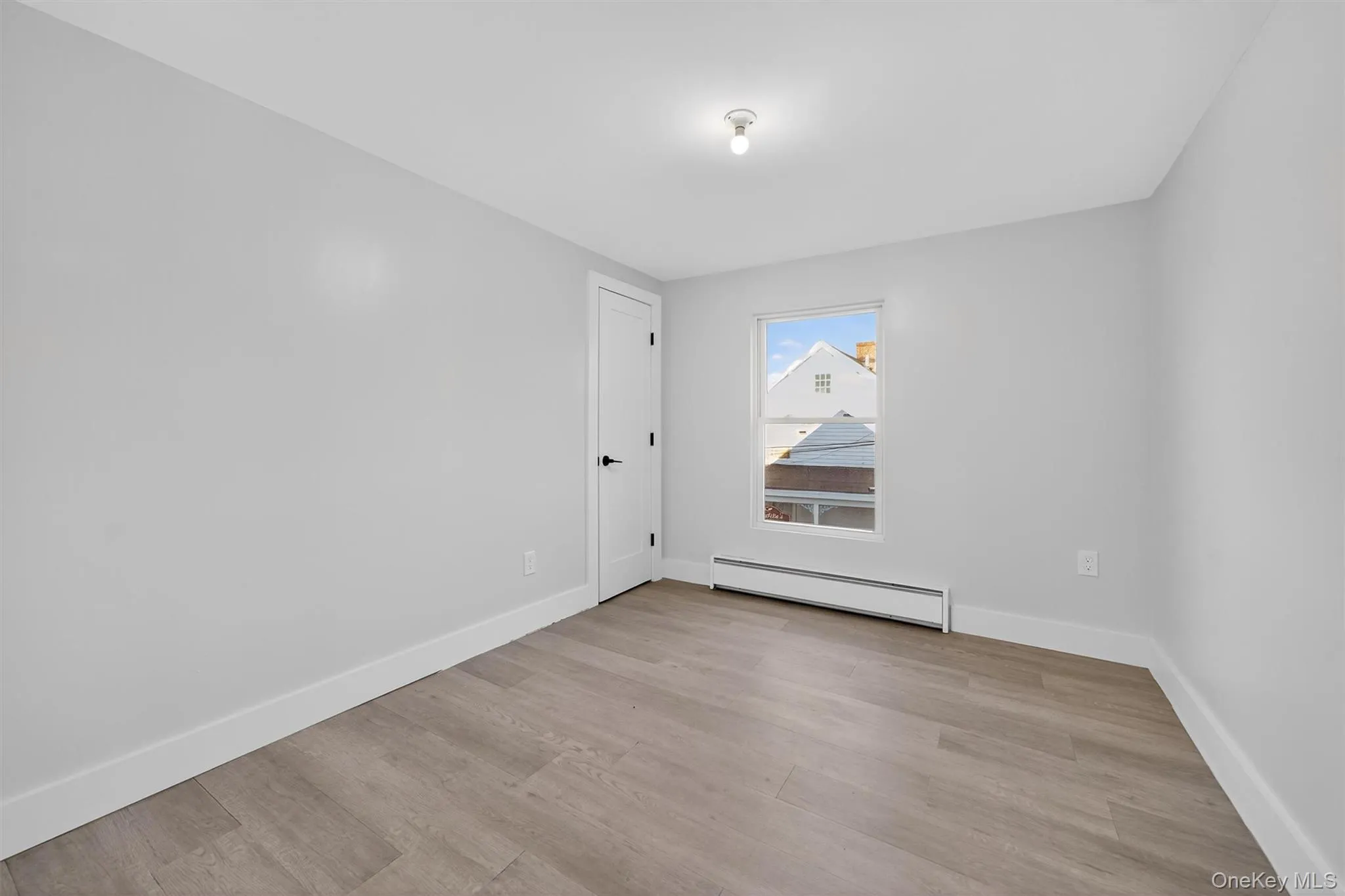 Empty room featuring baseboard heating and light wood-type flooring Empty room featuring baseboard heating and light wood-type flooring