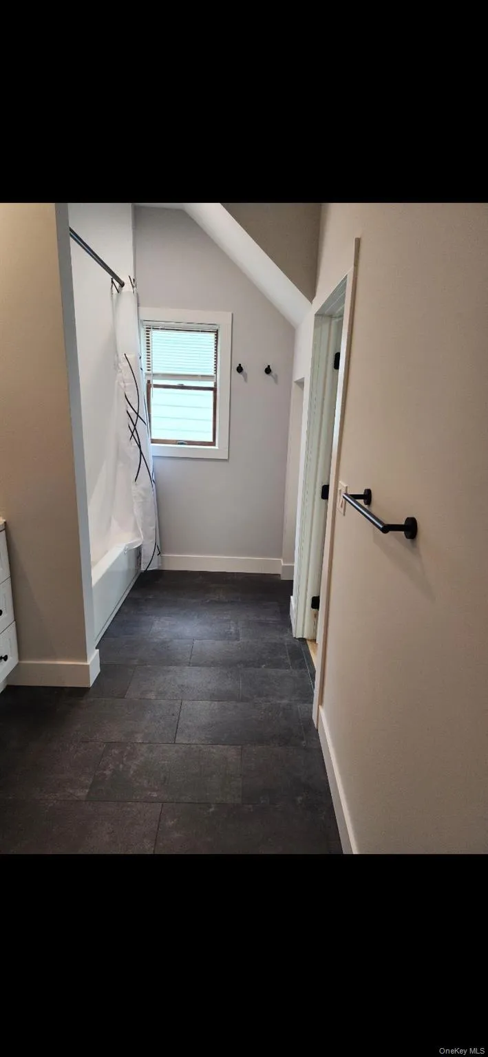 Full bathroom with vaulted ceiling, shower / bath combo with shower curtain, and vanity Full bathroom with vaulted ceiling, shower / bath combo with shower curtain, and vanity