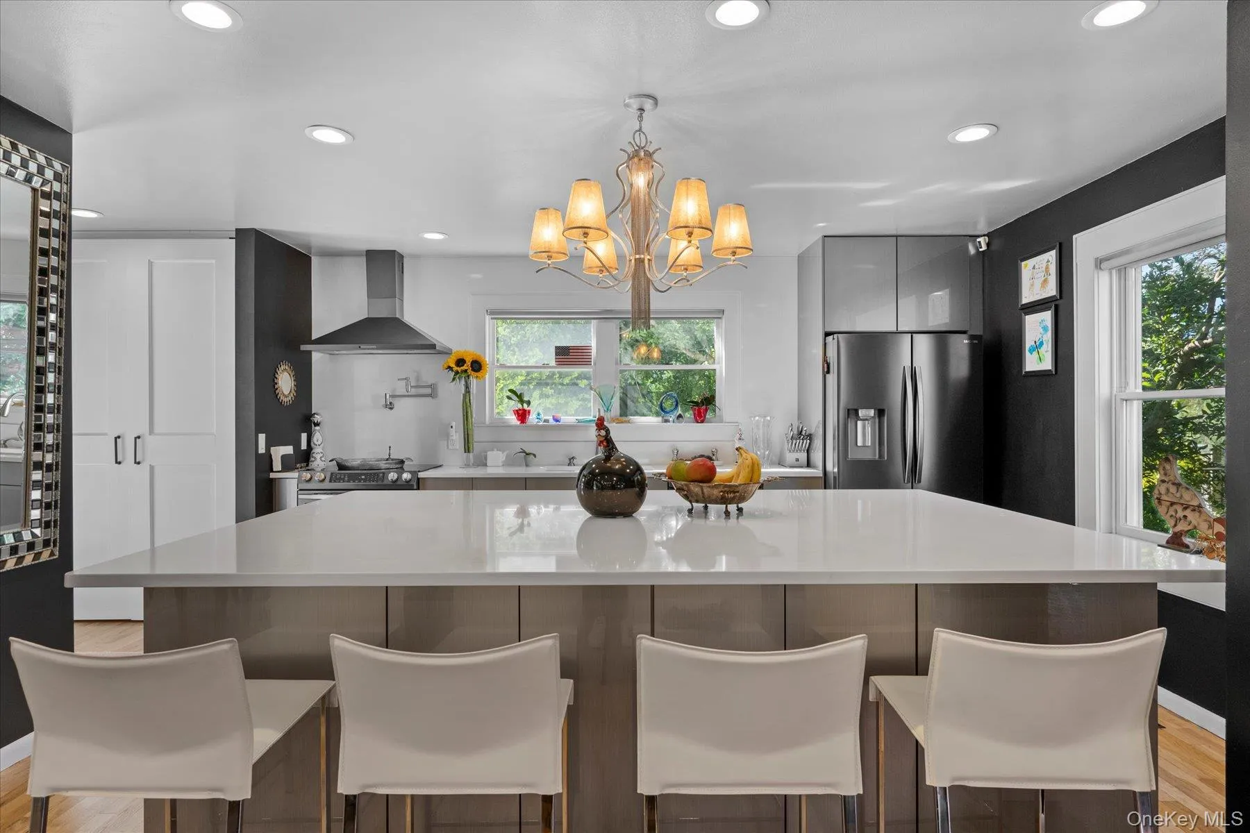 Kitchen featuring light wood-style flooring, recessed lighting, appliances with stainless steel finishes, a kitchen island, and hanging light fixtures Kitchen featuring light wood-style flooring, recessed lighting, appliances with stainless steel finishes, a kitchen island, and hanging light fixtures