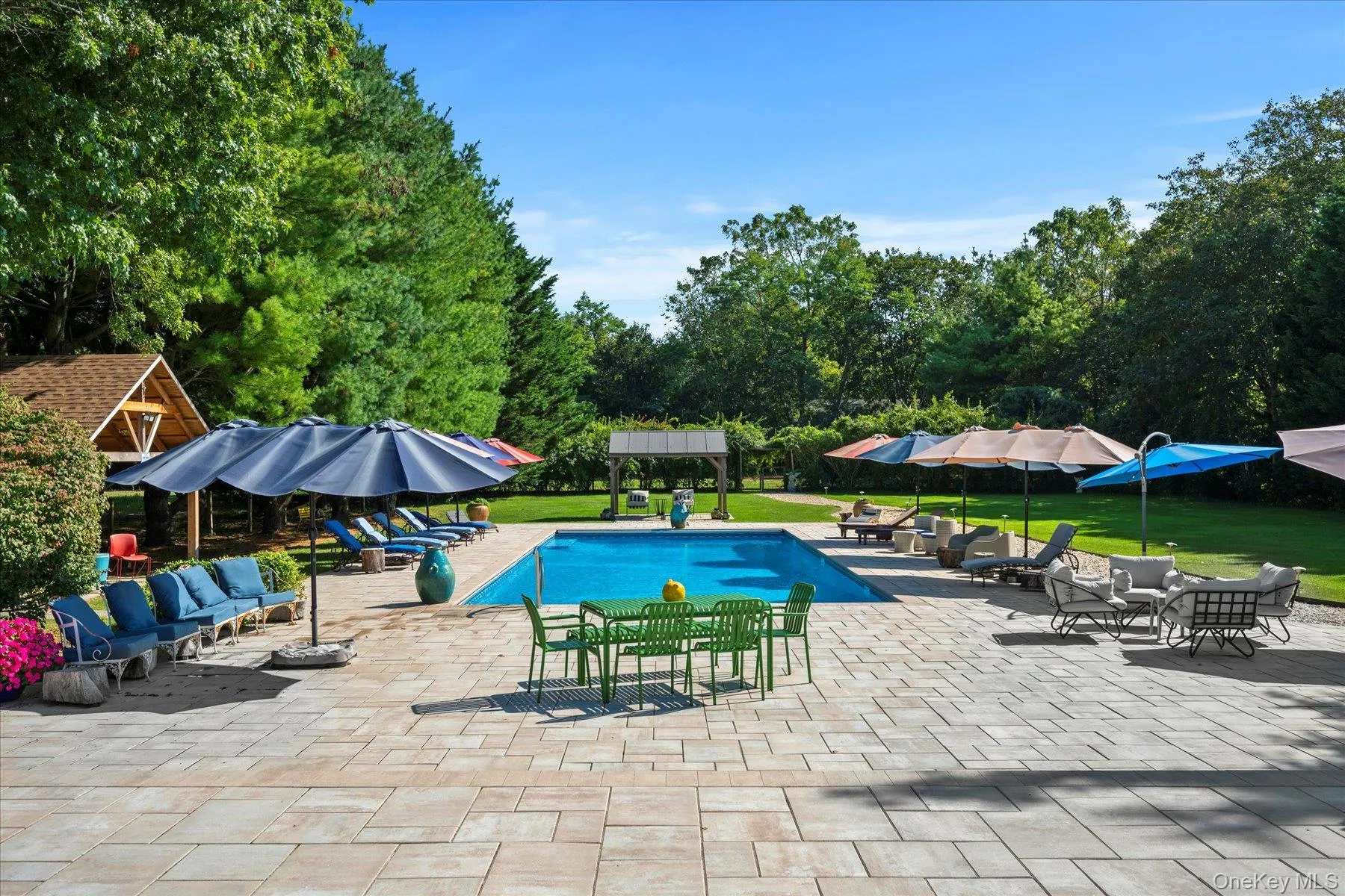 Outdoor pool with a lawn, a patio area, view of wooded area, an outdoor living space, and an outbuilding Outdoor pool with a lawn, a patio area, view of wooded area, an outdoor living space, and an outbuilding