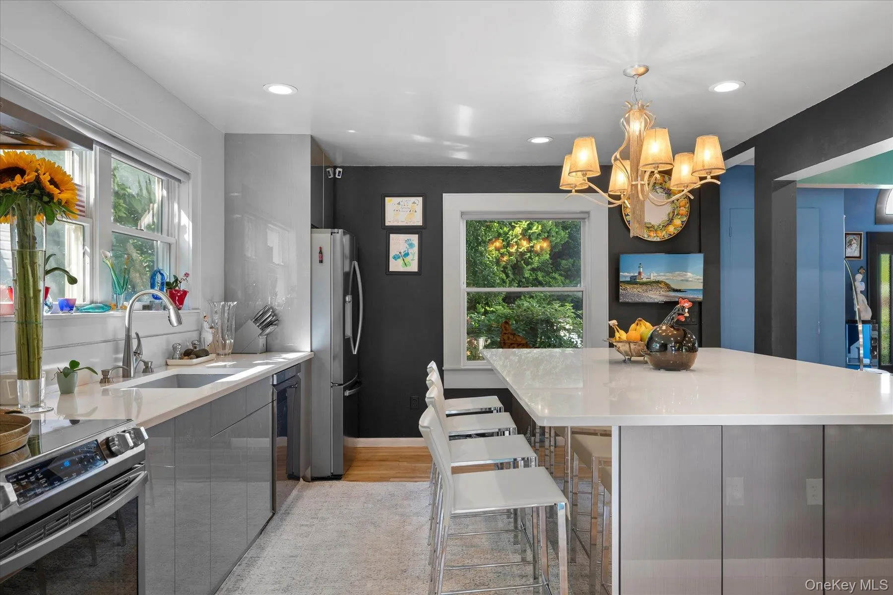 Kitchen with appliances with stainless steel finishes, hanging light fixtures, a breakfast bar, recessed lighting, and light stone counters Kitchen with appliances with stainless steel finishes, hanging light fixtures, a breakfast bar, recessed lighting, and light stone counters