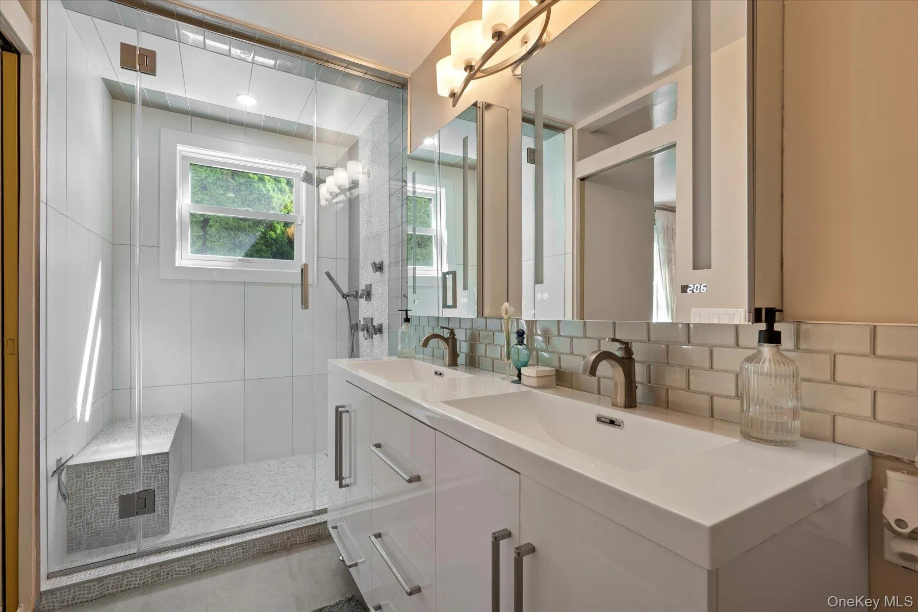 Bathroom with double vanity, backsplash, a shower stall, and tile walls Bathroom with double vanity, backsplash, a shower stall, and tile walls