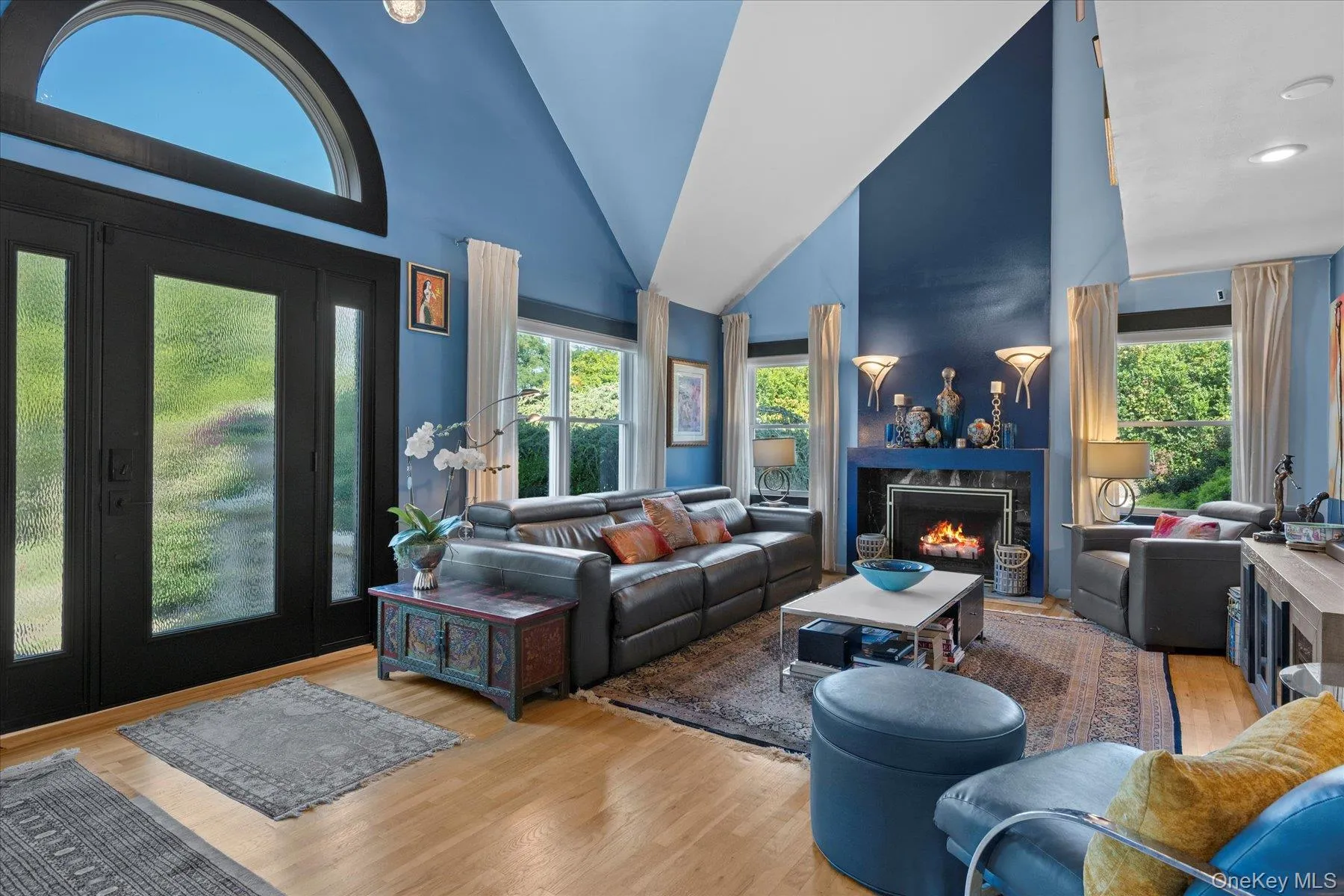 Entry and living room featuring high vaulted ceiling, wood finished floors, and fireplace Entry and living room featuring high vaulted ceiling, wood finished floors, and fireplace