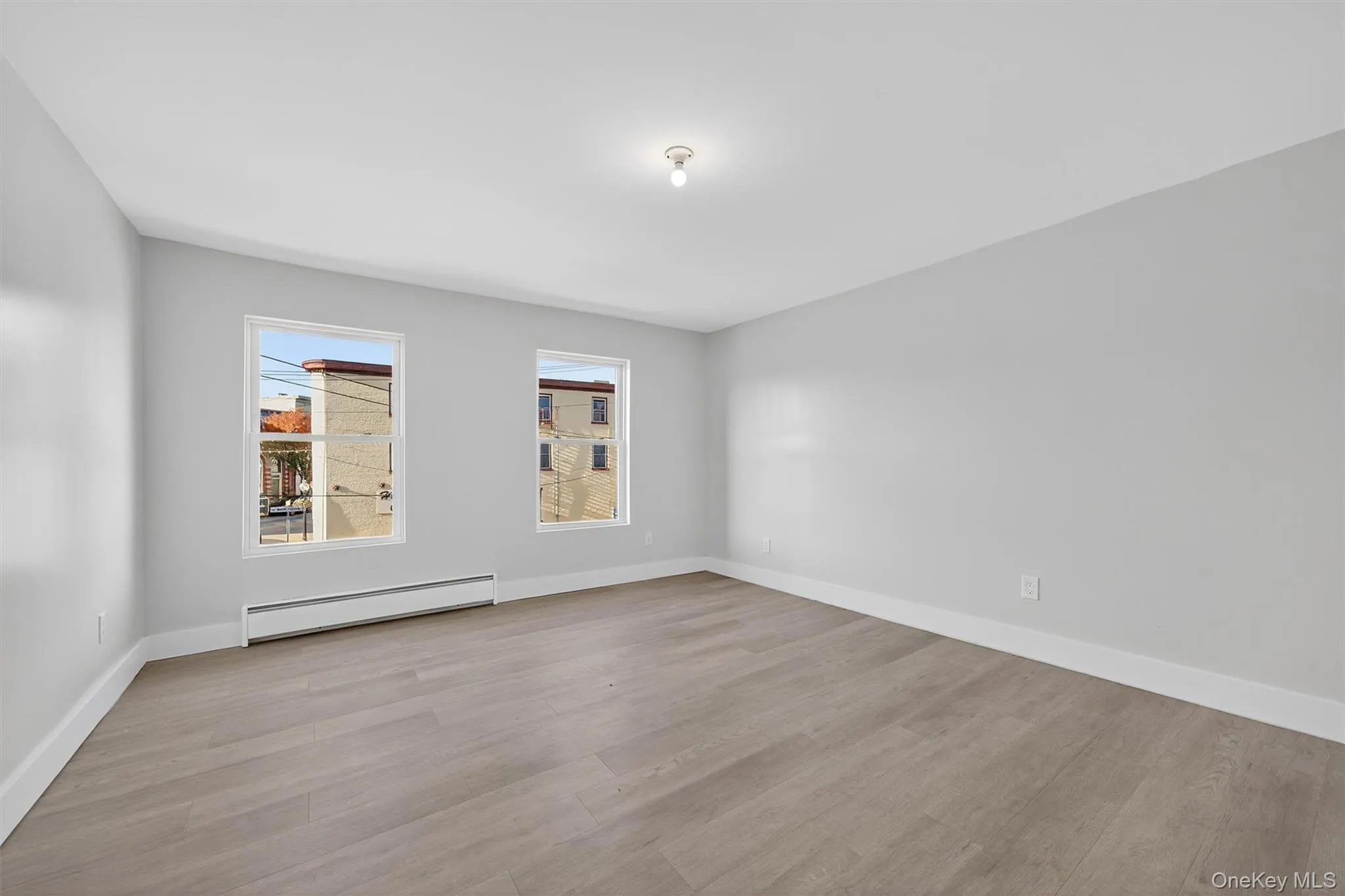 Empty room with baseboard heating and light wood-type flooring Empty room with baseboard heating and light wood-type flooring