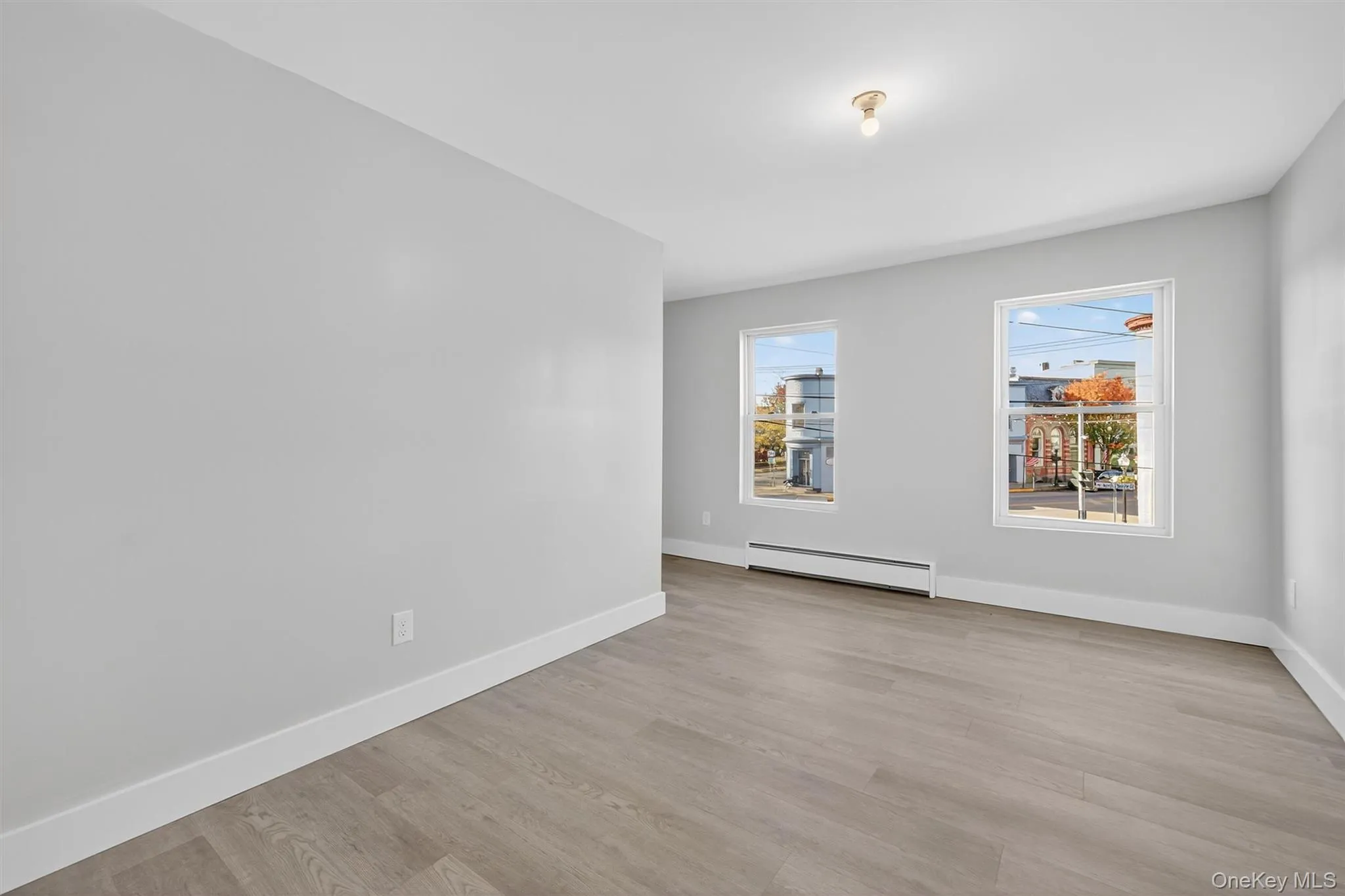 Empty room with light wood finished floors and a baseboard heating unit Empty room with light wood finished floors and a baseboard heating unit