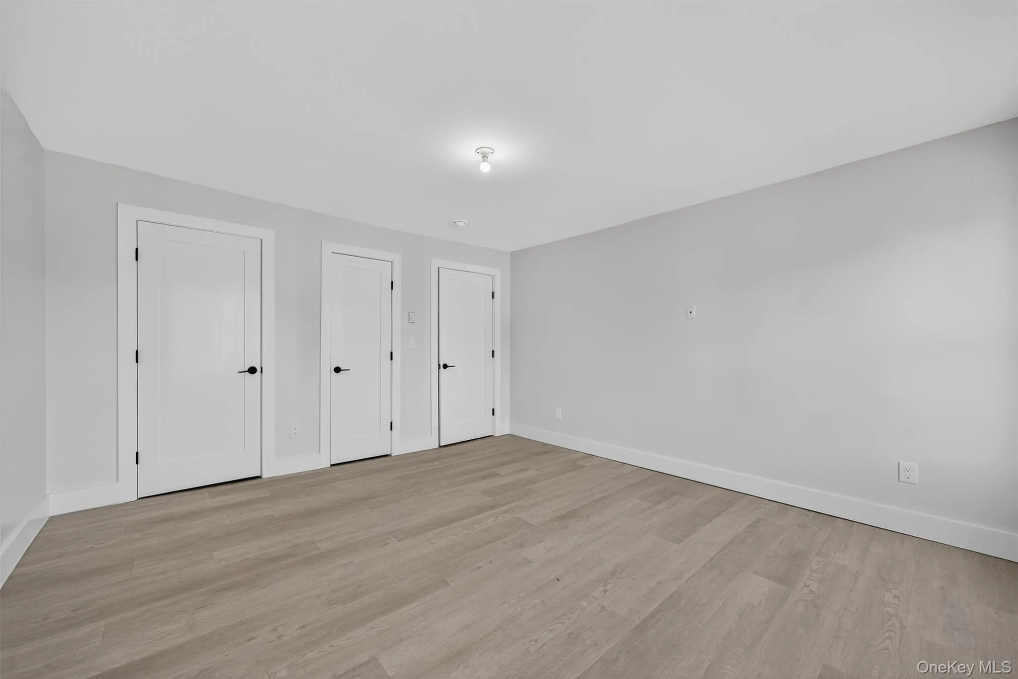 Unfurnished bedroom featuring multiple closets and light wood-style flooring Unfurnished bedroom featuring multiple closets and light wood-style flooring