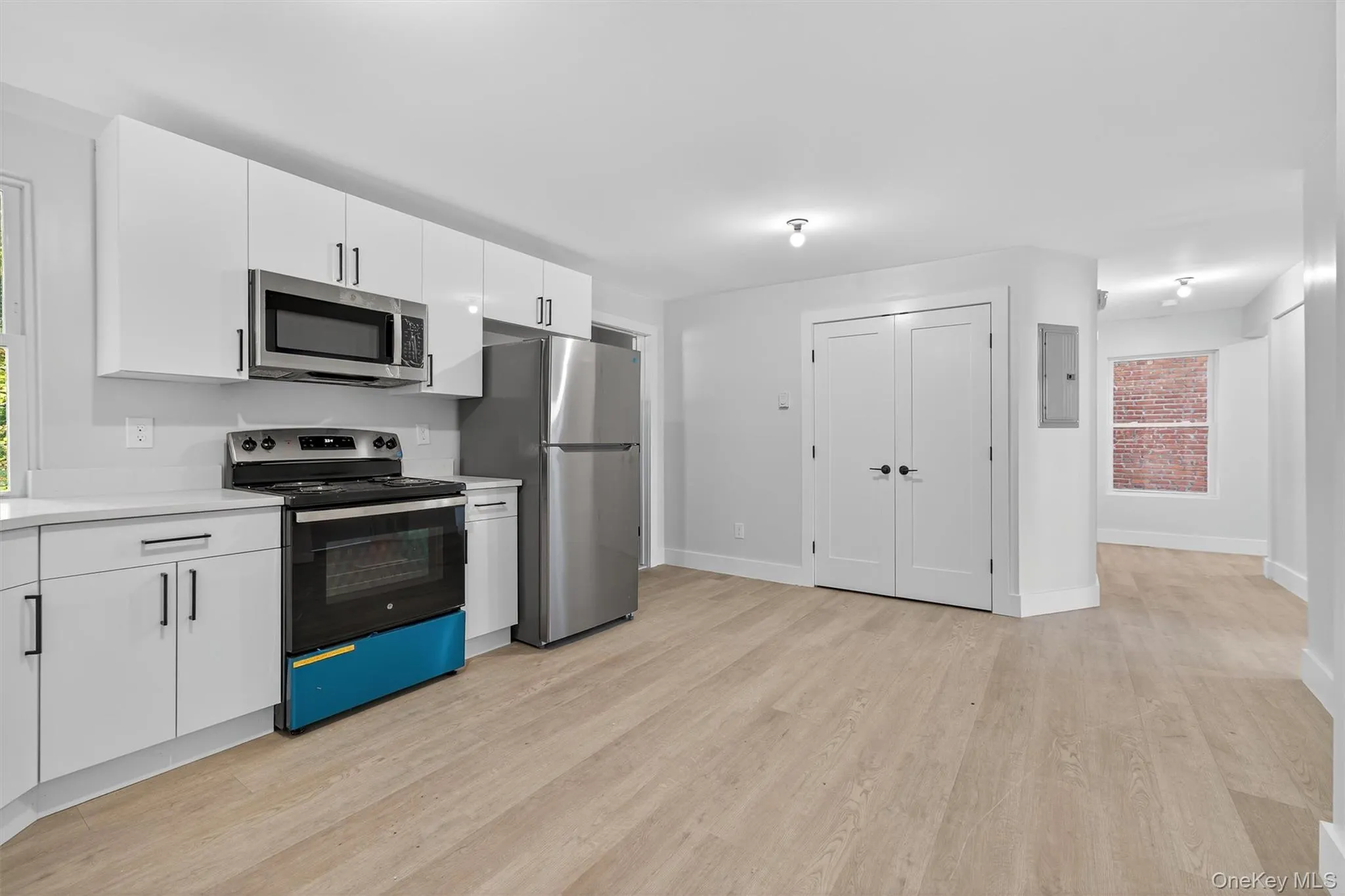 Kitchen featuring appliances with stainless steel finishes, white cabinets, light countertops, light wood finished floors, and electric panel Kitchen featuring appliances with stainless steel finishes, white cabinets, light countertops, light wood finished floors, and electric panel