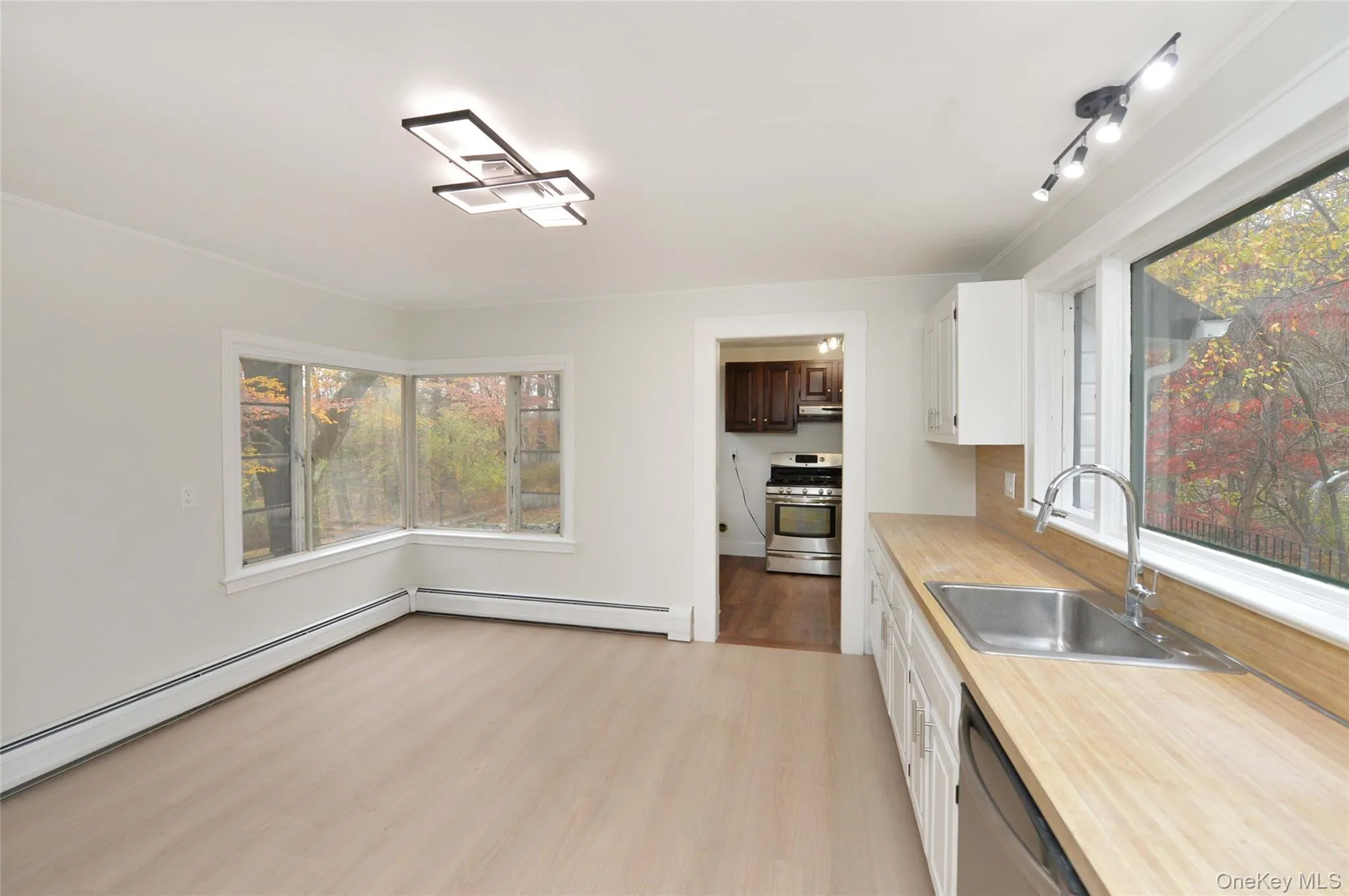 Kitchen featuring light countertops, light wood finished floors, white cabinets, stainless steel appliances, and baseboard heating Kitchen featuring light countertops, light wood finished floors, white cabinets, stainless steel appliances, and baseboard heating