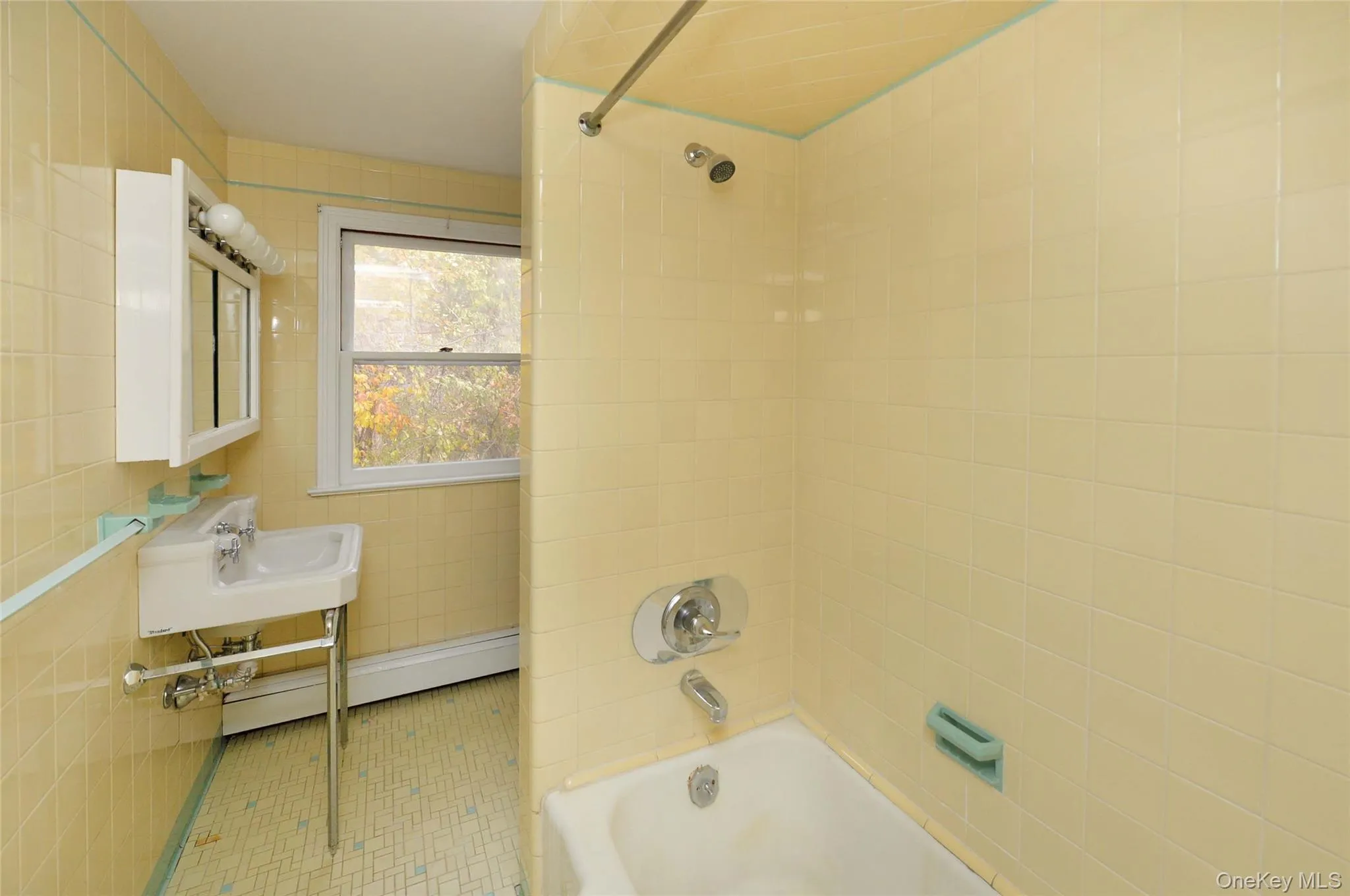Full bath with tub / shower combination, tile walls, tile patterned floors, and a baseboard radiator Full bath with tub / shower combination, tile walls, tile patterned floors, and a baseboard radiator