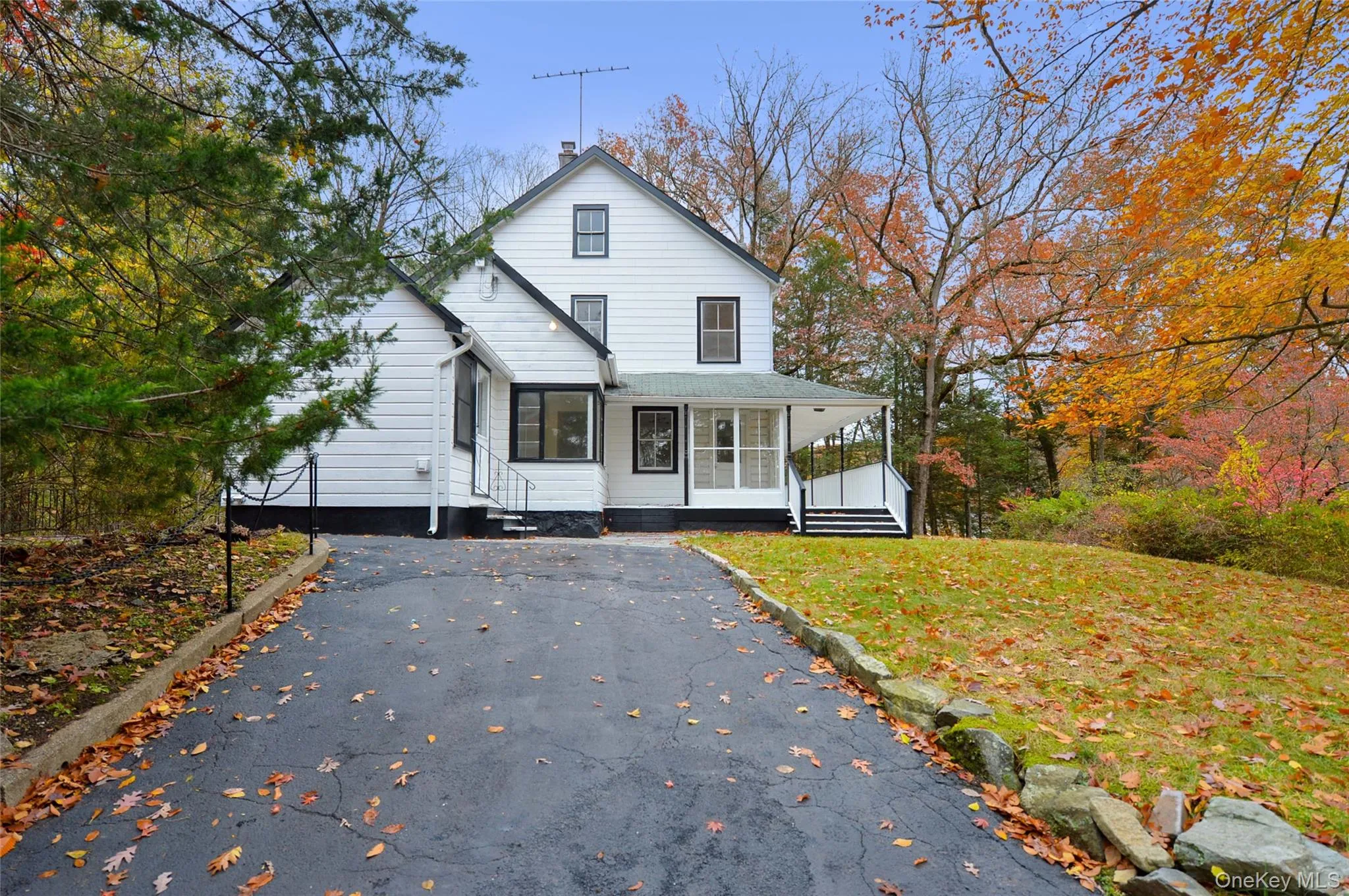 View of front of house featuring driveway, a chimney, covered porch, and a front yard View of front of house featuring driveway, a chimney, covered porch, and a front yard
