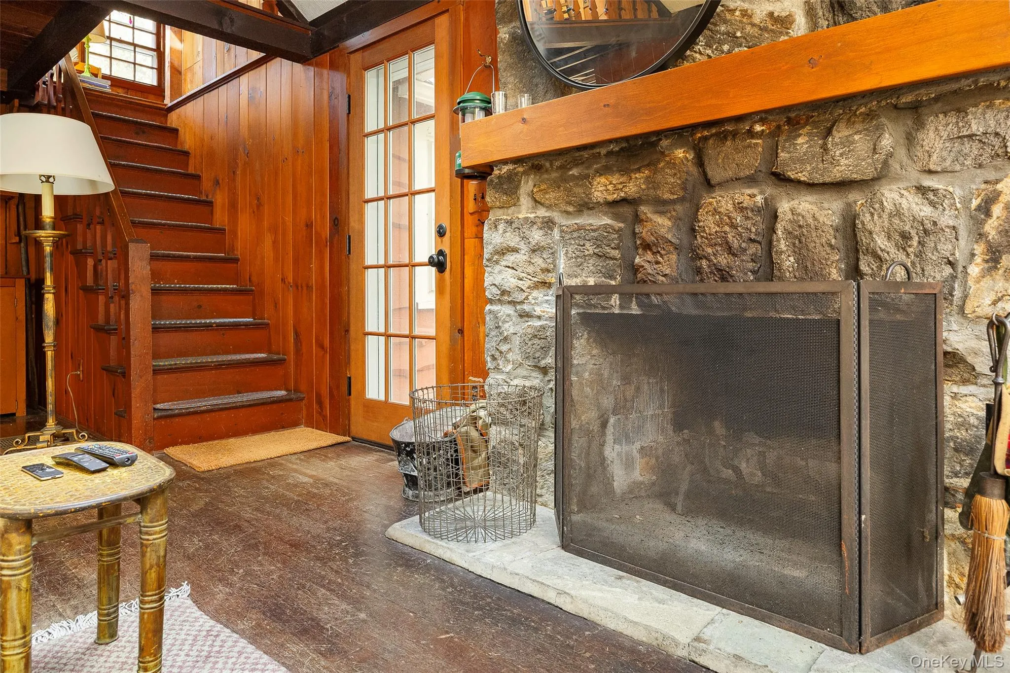Living room featuring wooden walls, a skylight, a fireplace, beam ceiling, and wood finished floors Living room featuring wooden walls, a skylight, a fireplace, beam ceiling, and wood finished floors