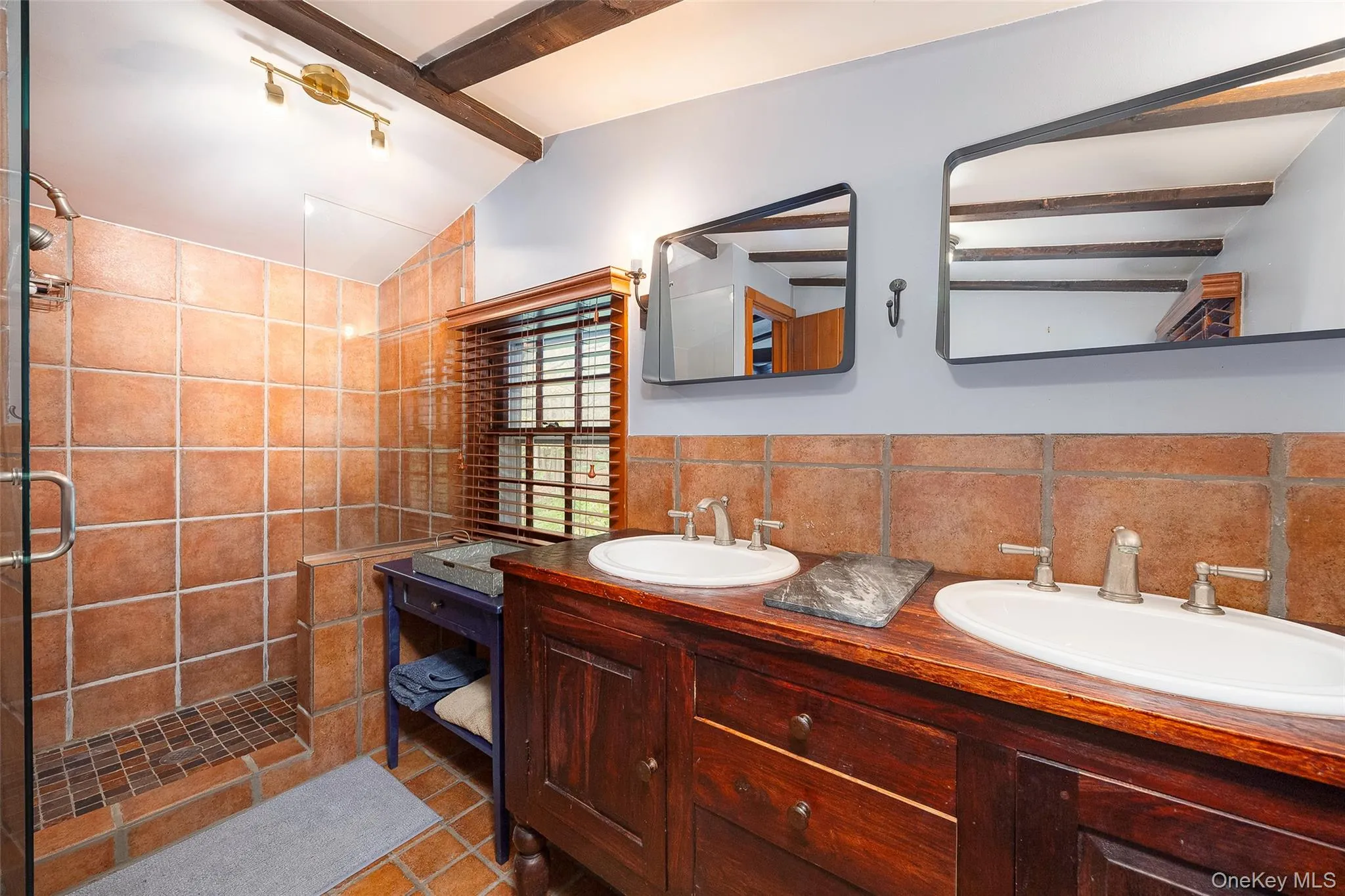 Full bath with double vanity, a stall shower, tasteful backsplash, tile walls, and tile patterned flooring Full bath with double vanity, a stall shower, tasteful backsplash, tile walls, and tile patterned flooring