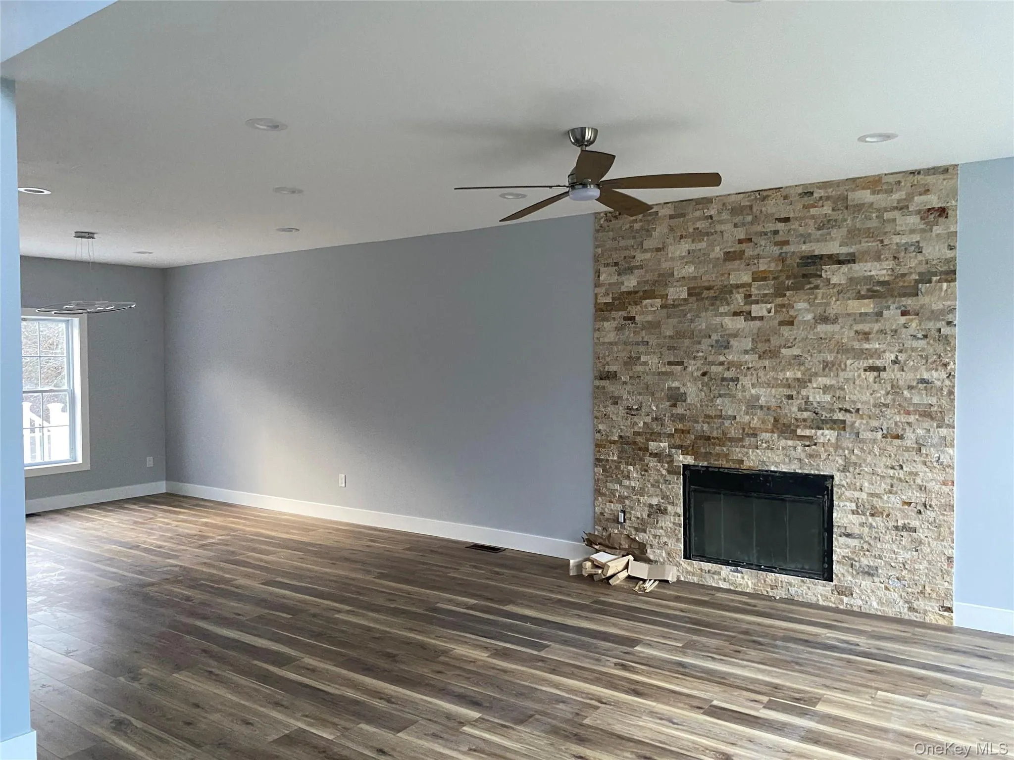 Unfurnished living room featuring a large fireplace, dark wood finished floors, ceiling fan, and recessed lighting Unfurnished living room featuring a large fireplace, dark wood finished floors, ceiling fan, and recessed lighting