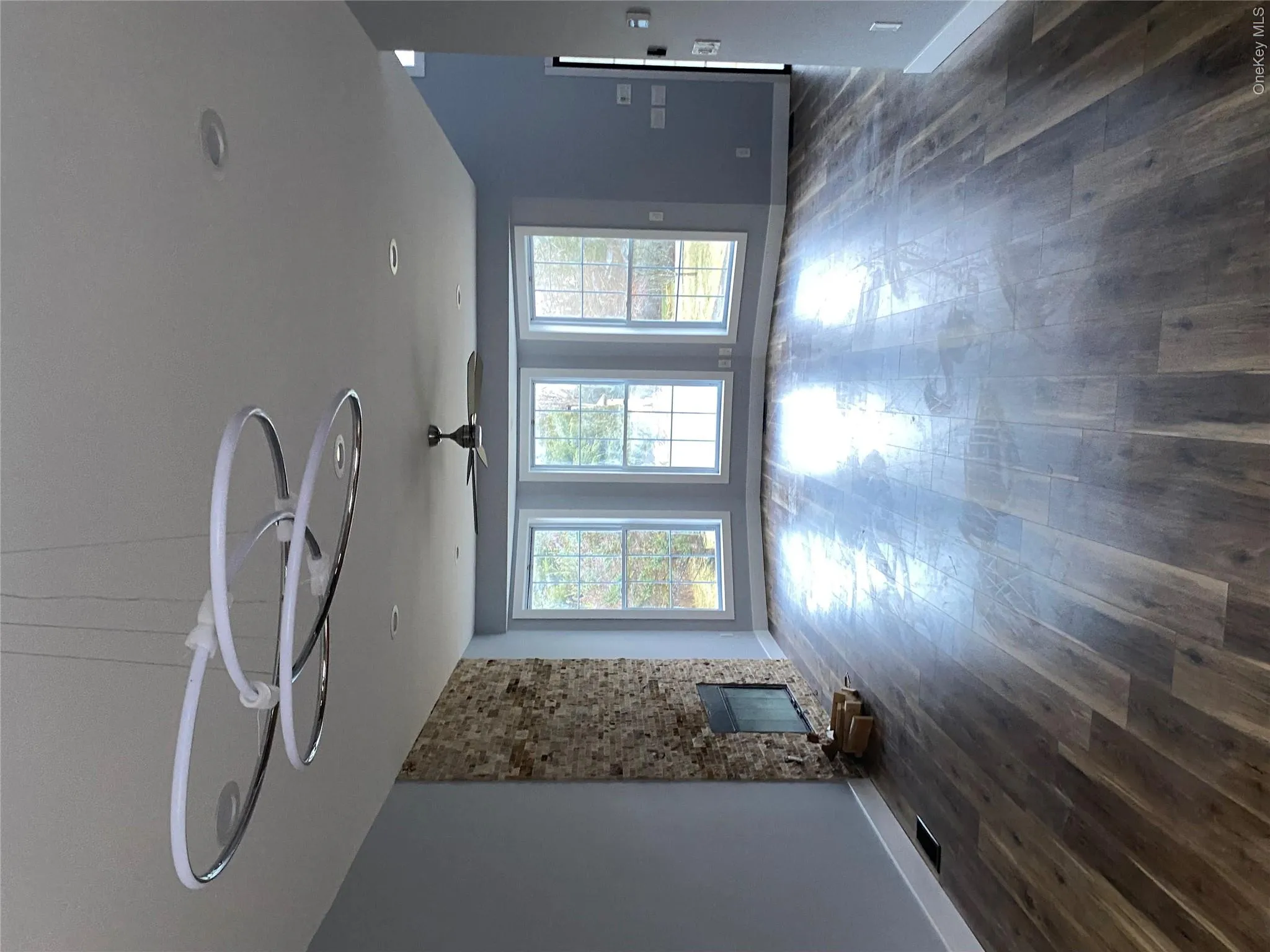 Unfurnished living room featuring dark wood-style flooring, ceiling fan, a stone fireplace, and a chandelier Unfurnished living room featuring dark wood-style flooring, ceiling fan, a stone fireplace, and a chandelier