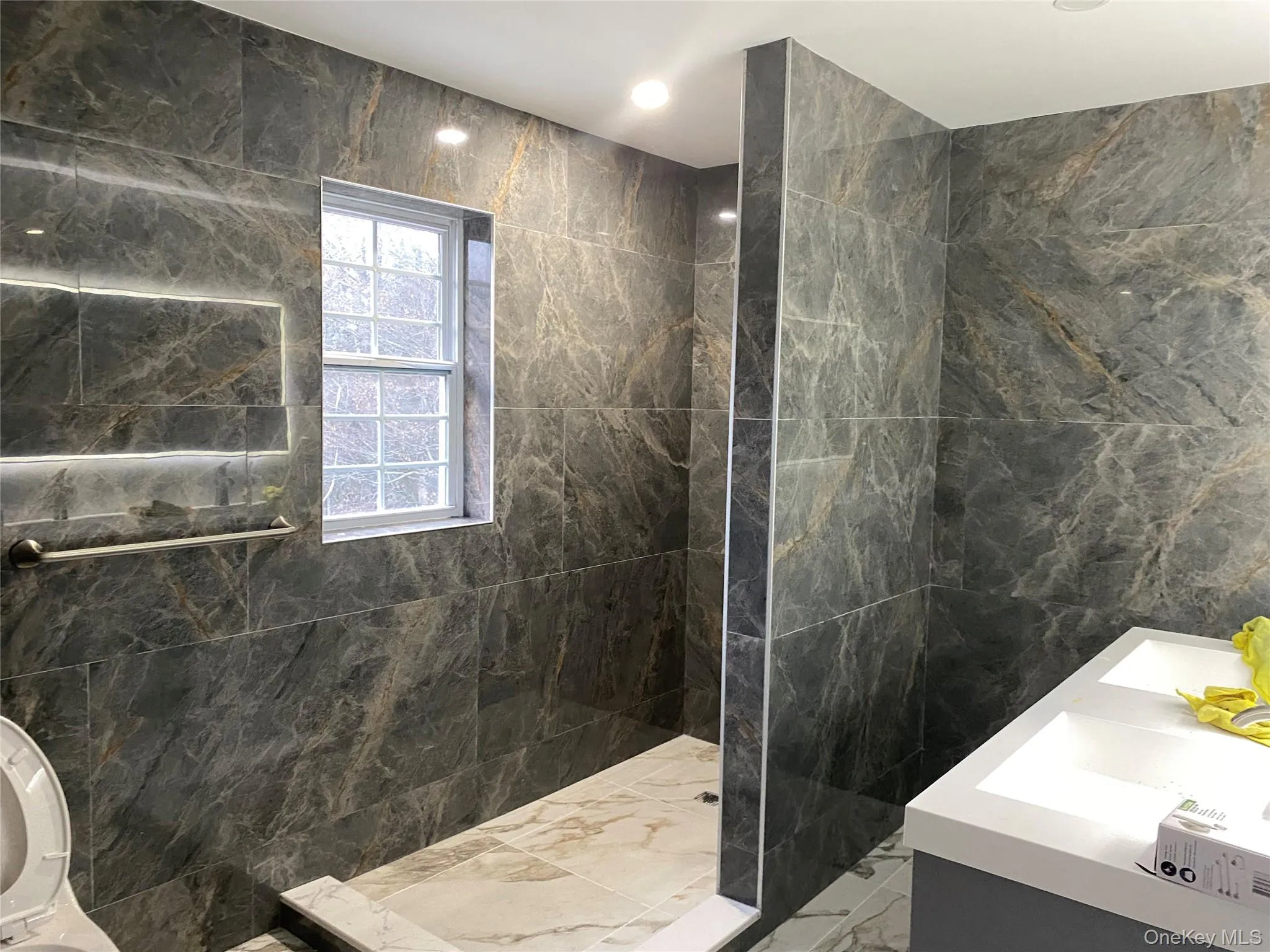 Bathroom featuring tile walls, marble tiled flooring, vanity, a marble finish shower, and recessed lighting Bathroom featuring tile walls, marble tiled flooring, vanity, a marble finish shower, and recessed lighting