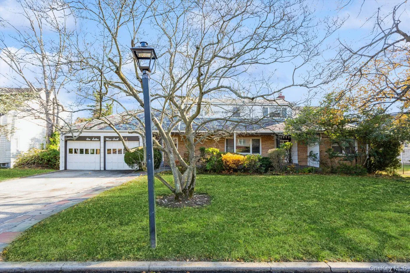 View of front facade featuring concrete driveway, a front lawn, brick siding, a chimney, and a garage View of front facade featuring concrete driveway, a front lawn, brick siding, a chimney, and a garage