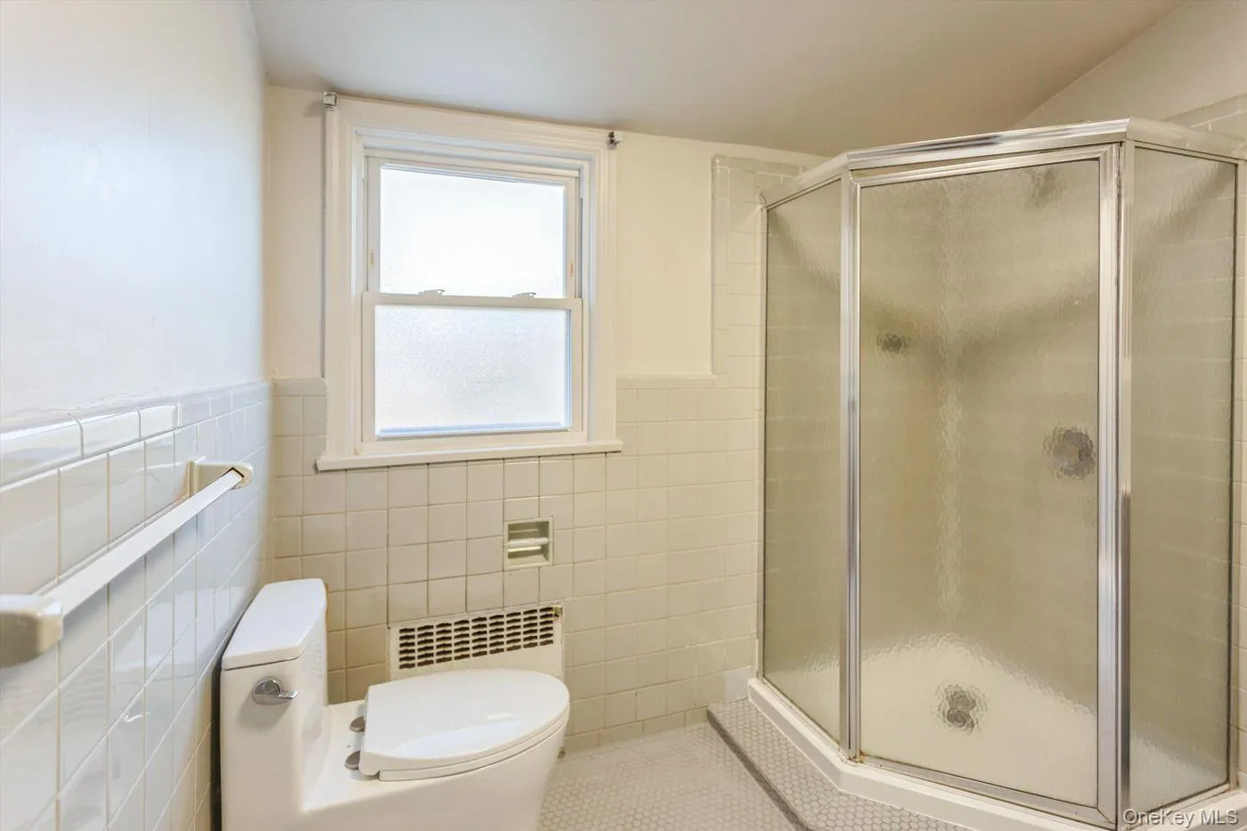 Full bathroom featuring a stall shower, wainscoting, tile patterned flooring, radiator, and tile walls Full bathroom featuring a stall shower, wainscoting, tile patterned flooring, radiator, and tile walls