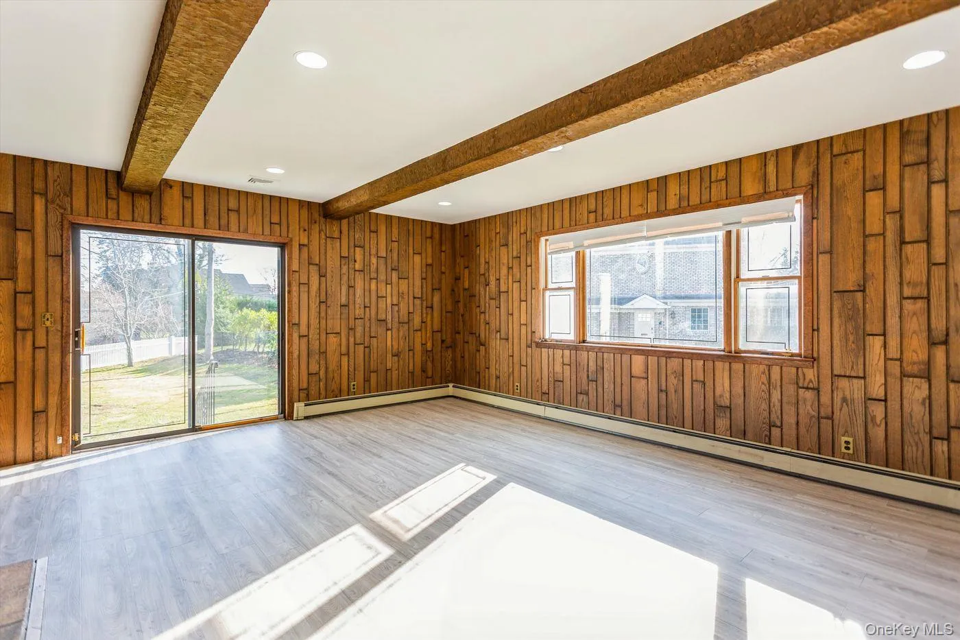 Empty room with wood walls, recessed lighting, a baseboard heating unit, light wood-style flooring, and beamed ceiling Empty room with wood walls, recessed lighting, a baseboard heating unit, light wood-style flooring, and beamed ceiling