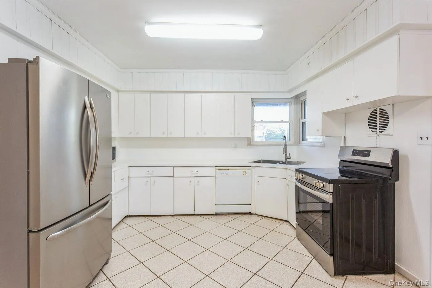 Kitchen with appliances with stainless steel finishes, light countertops, light tile patterned flooring, and white cabinets Kitchen with appliances with stainless steel finishes, light countertops, light tile patterned flooring, and white cabinets
