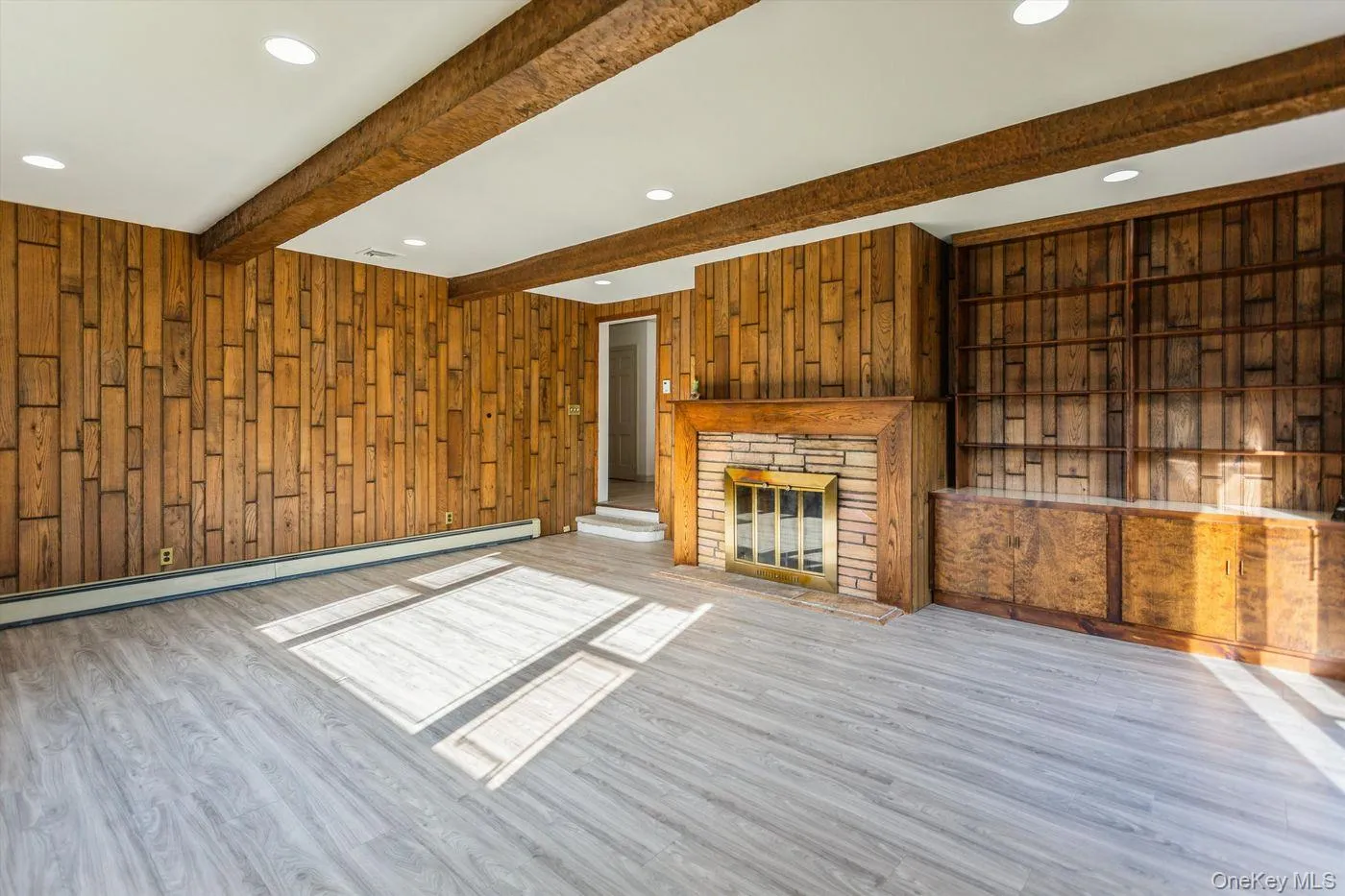 Unfurnished living room with wood walls, wood finished floors, recessed lighting, a glass covered fireplace, and beam ceiling Unfurnished living room with wood walls, wood finished floors, recessed lighting, a glass covered fireplace, and beam ceiling