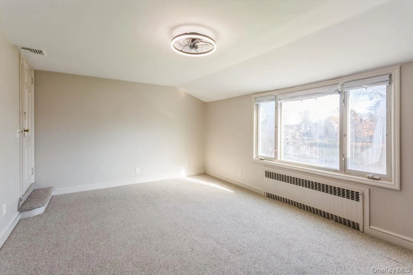 Unfurnished room with radiator heating unit and light colored carpet Unfurnished room with radiator heating unit and light colored carpet