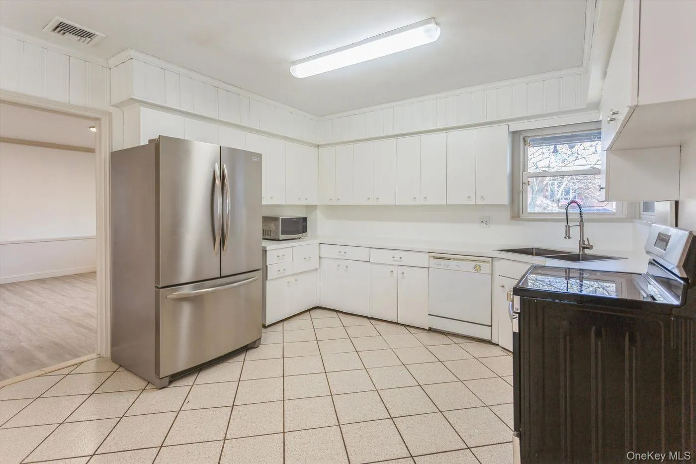 Kitchen with appliances with stainless steel finishes, light tile patterned floors, white cabinetry, and light countertops Kitchen with appliances with stainless steel finishes, light tile patterned floors, white cabinetry, and light countertops