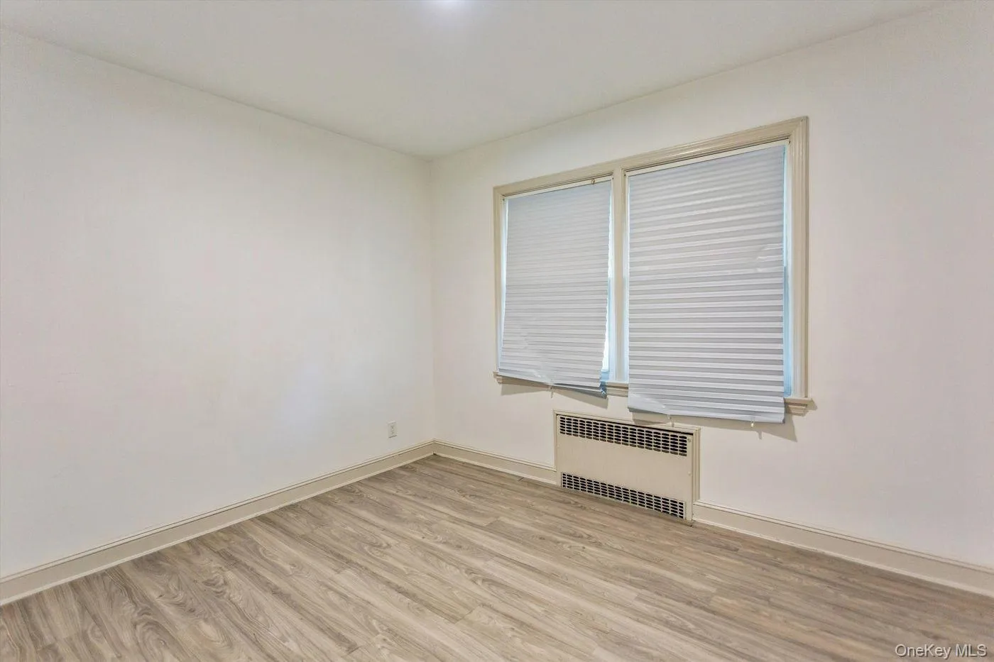 Spare room with radiator and light wood finished floors Spare room with radiator and light wood finished floors