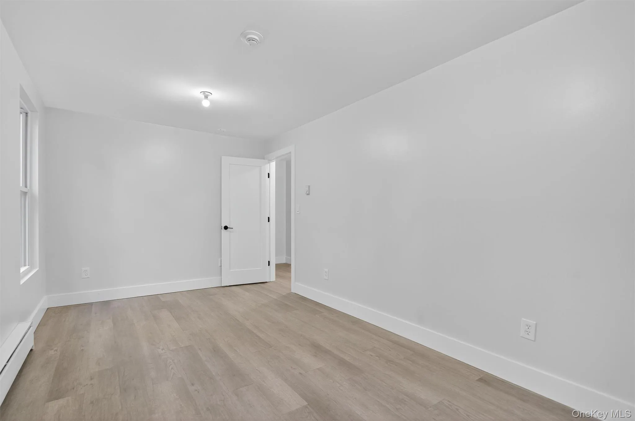 Unfurnished room with light wood-type flooring and a baseboard heating unit Unfurnished room with light wood-type flooring and a baseboard heating unit