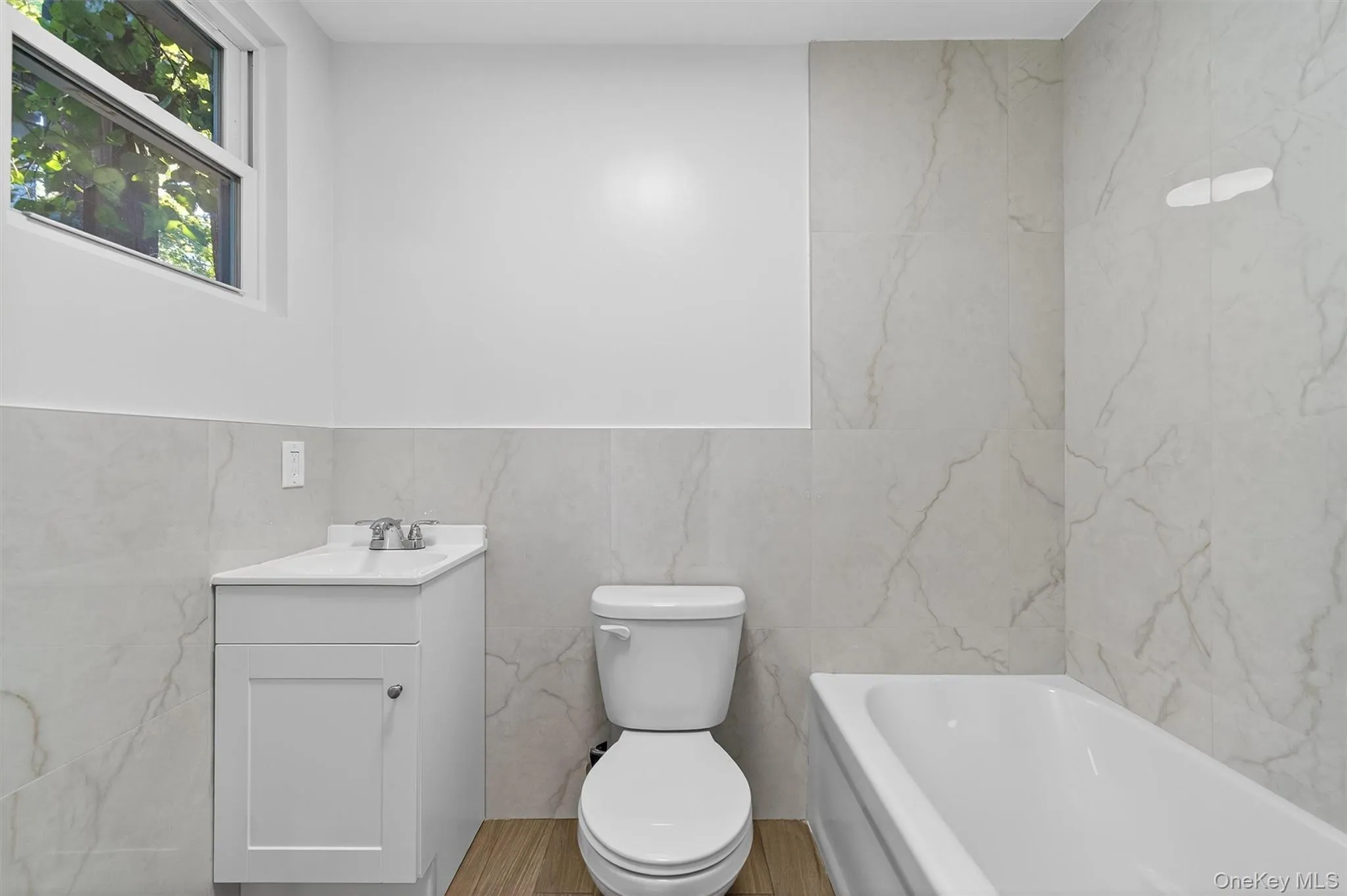 Bathroom featuring tile walls, vanity, and a tub Bathroom featuring tile walls, vanity, and a tub
